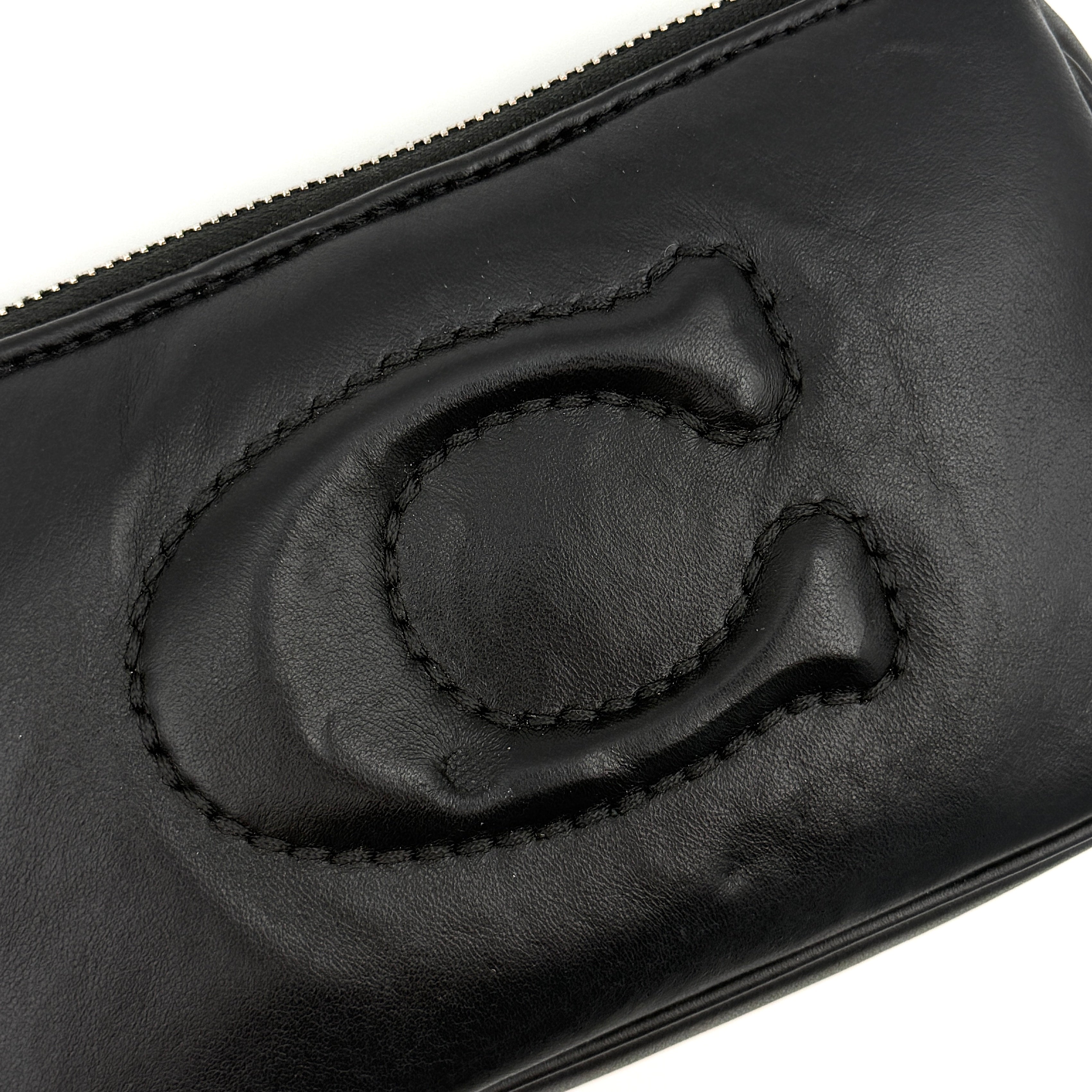 Coach Nolita 19 shoulder bag in quilted black leather with a bold stitched 'C' emblem and chunky silver chain strap.
