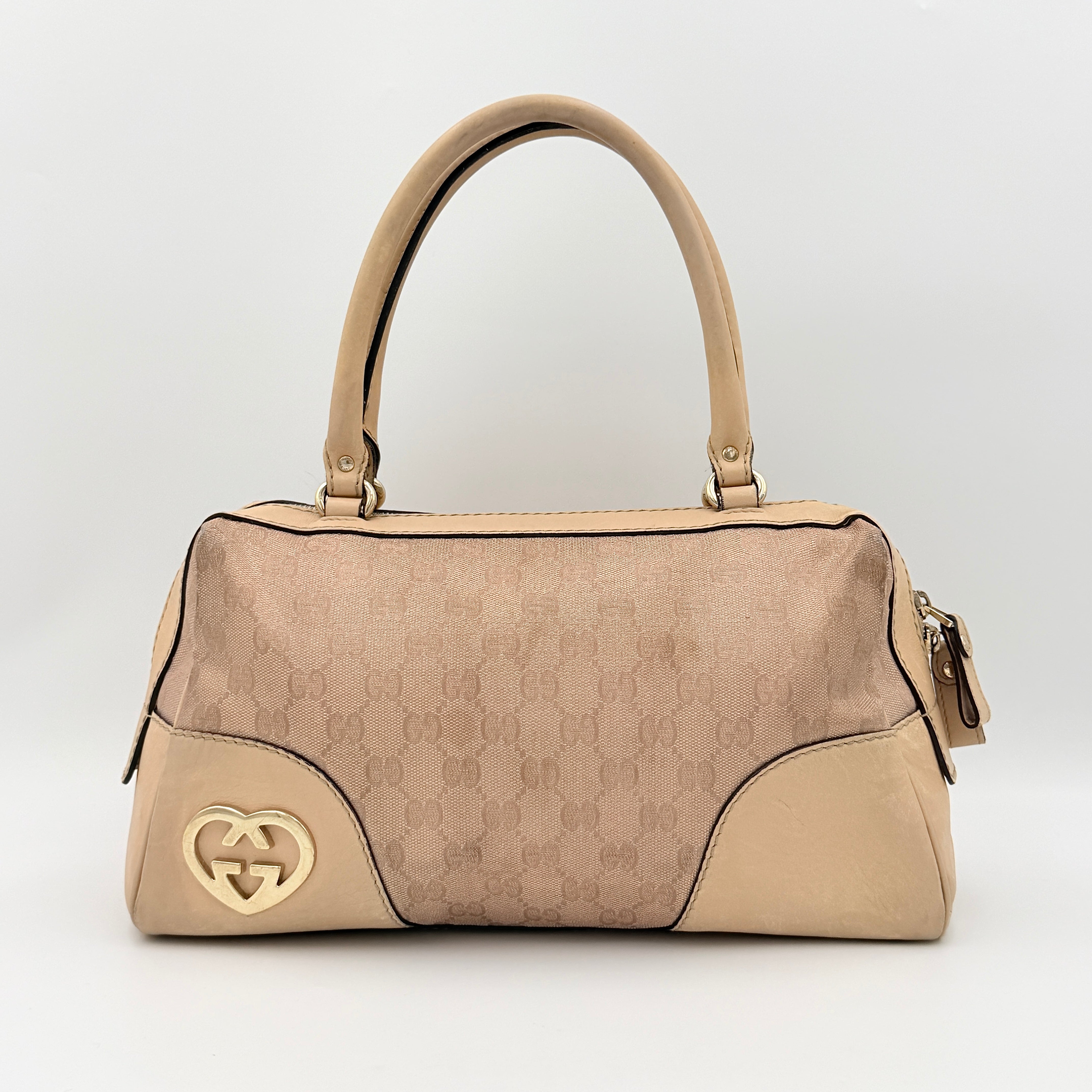 Gucci GG Monogram Heart Lovely Boston Bag in beige and pink with gold heart logo and double handles, displayed against a plain background.