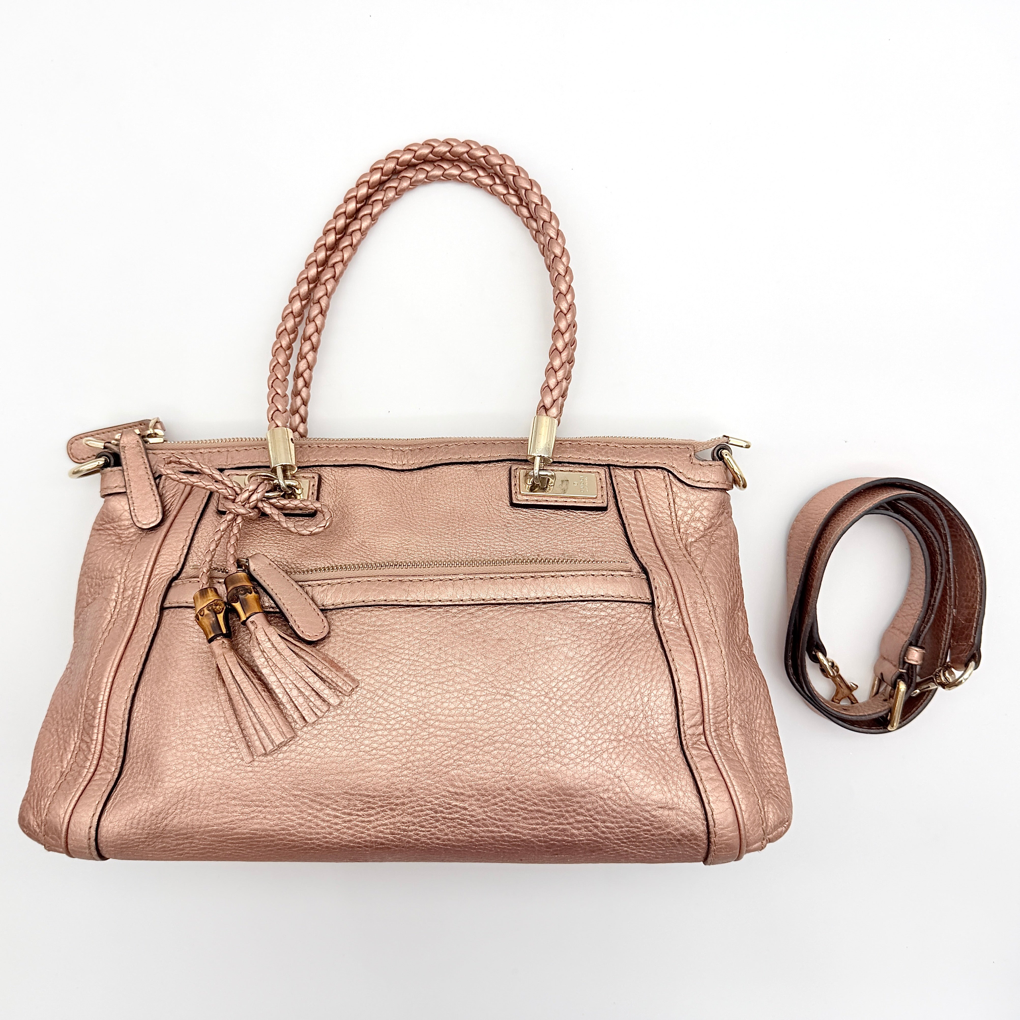Gucci Bella Bamboo 2Way shoulder bag in metallic pink leather with braided handles and bamboo tassel accents, displayed with a detachable strap.