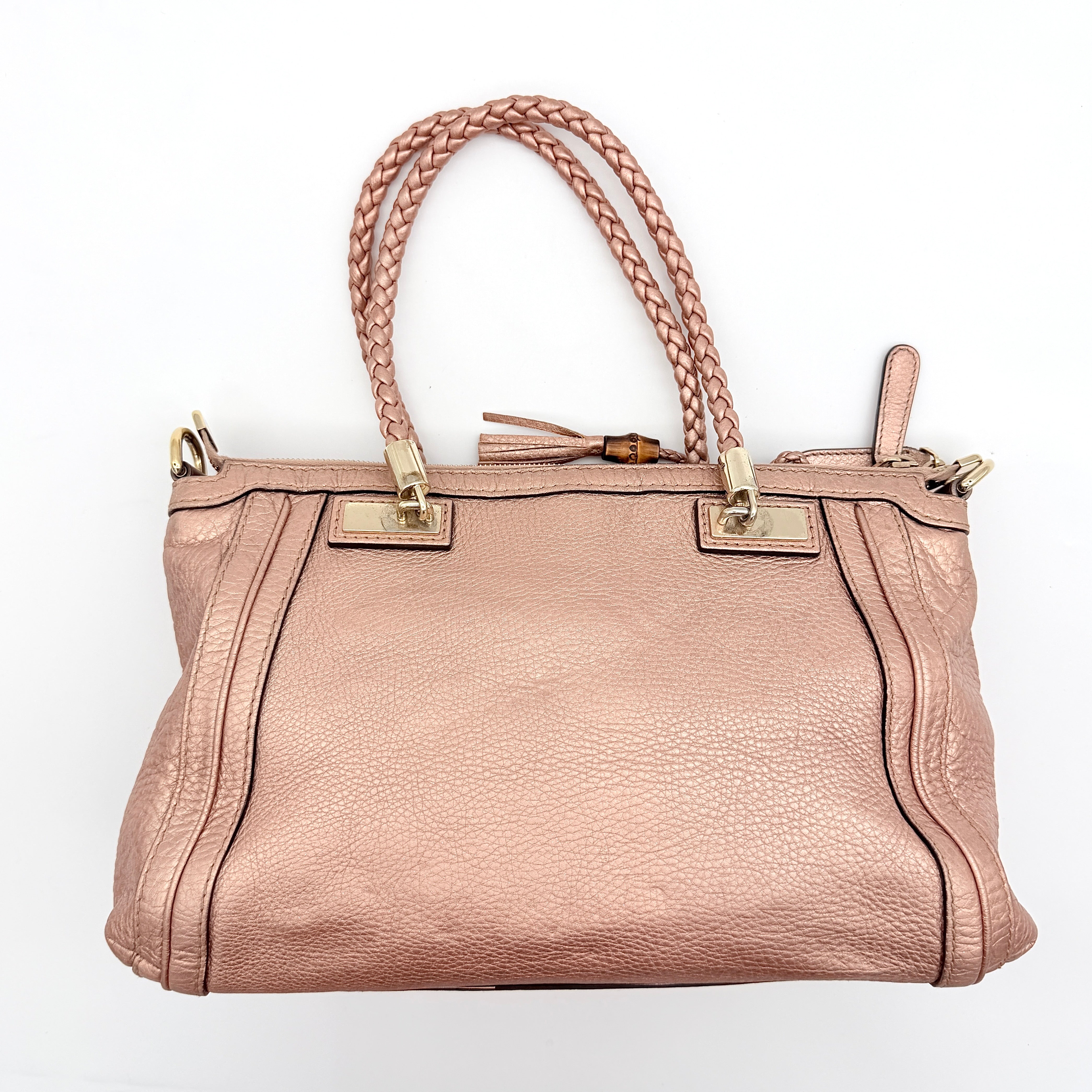 Gucci Bella Bamboo 2Way shoulder bag in metallic pink leather with braided handles and bamboo tassel accents, displayed with a detachable strap.