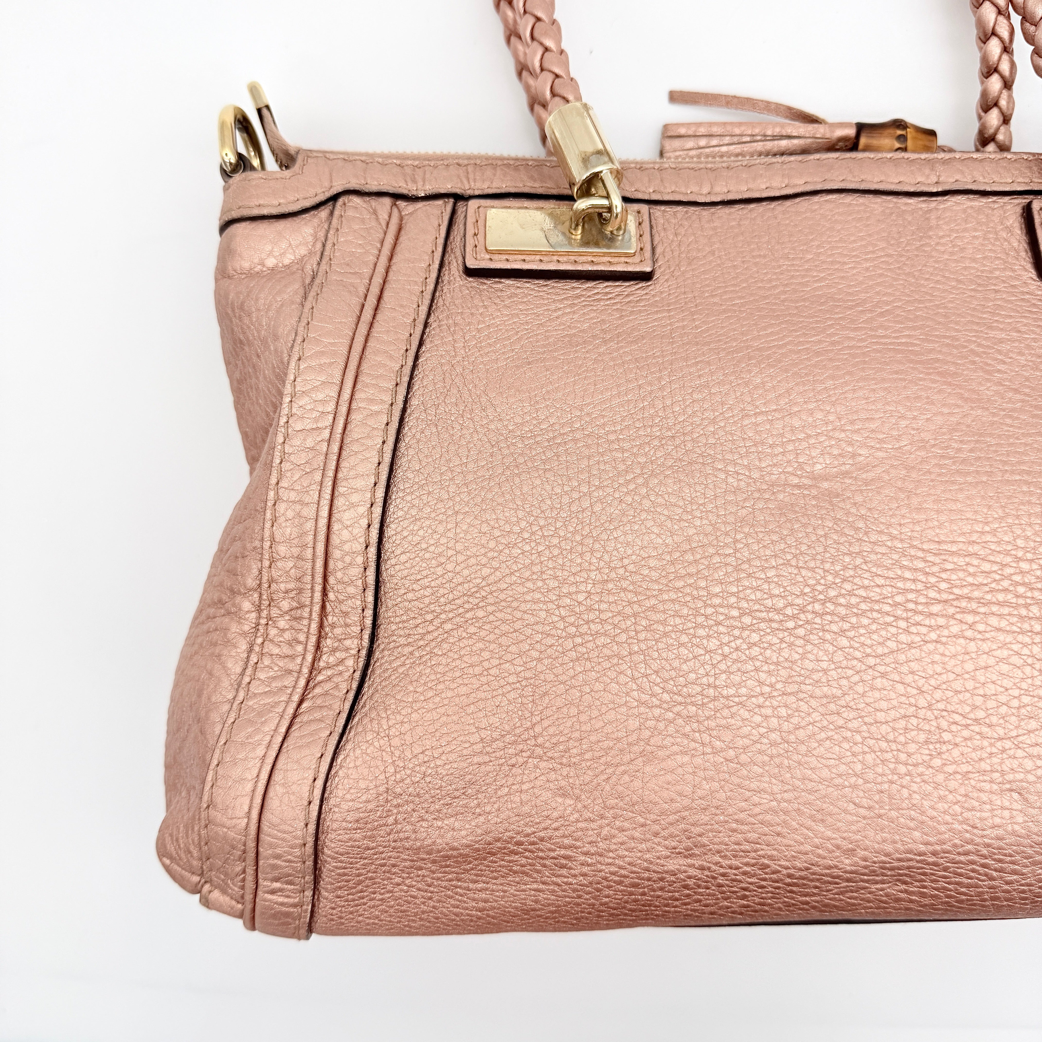 Gucci Bella Bamboo 2Way shoulder bag in metallic pink leather with braided handles and bamboo tassel accents, displayed with a detachable strap.