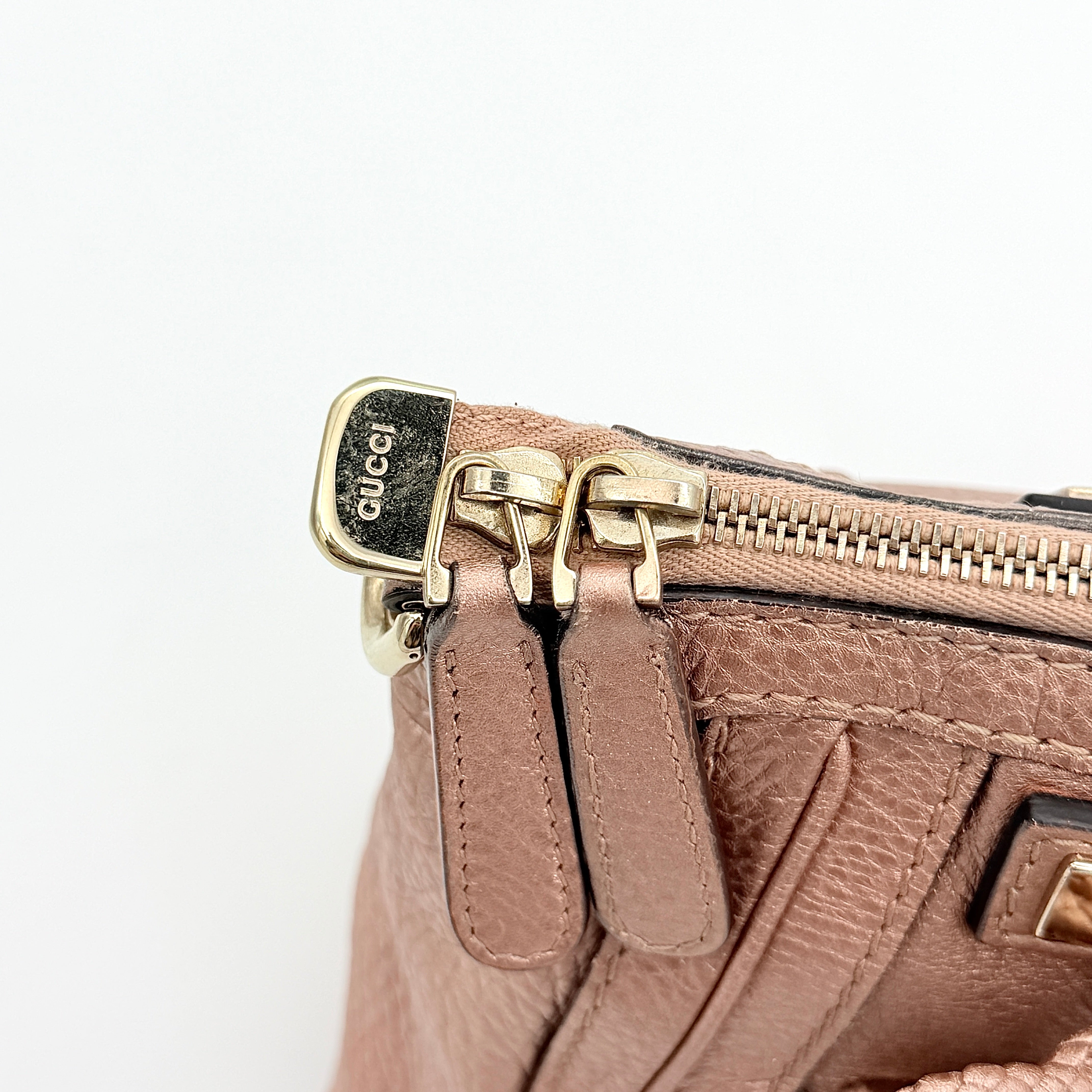 Gucci Bella Bamboo 2Way shoulder bag in metallic pink leather with braided handles and bamboo tassel accents, displayed with a detachable strap.