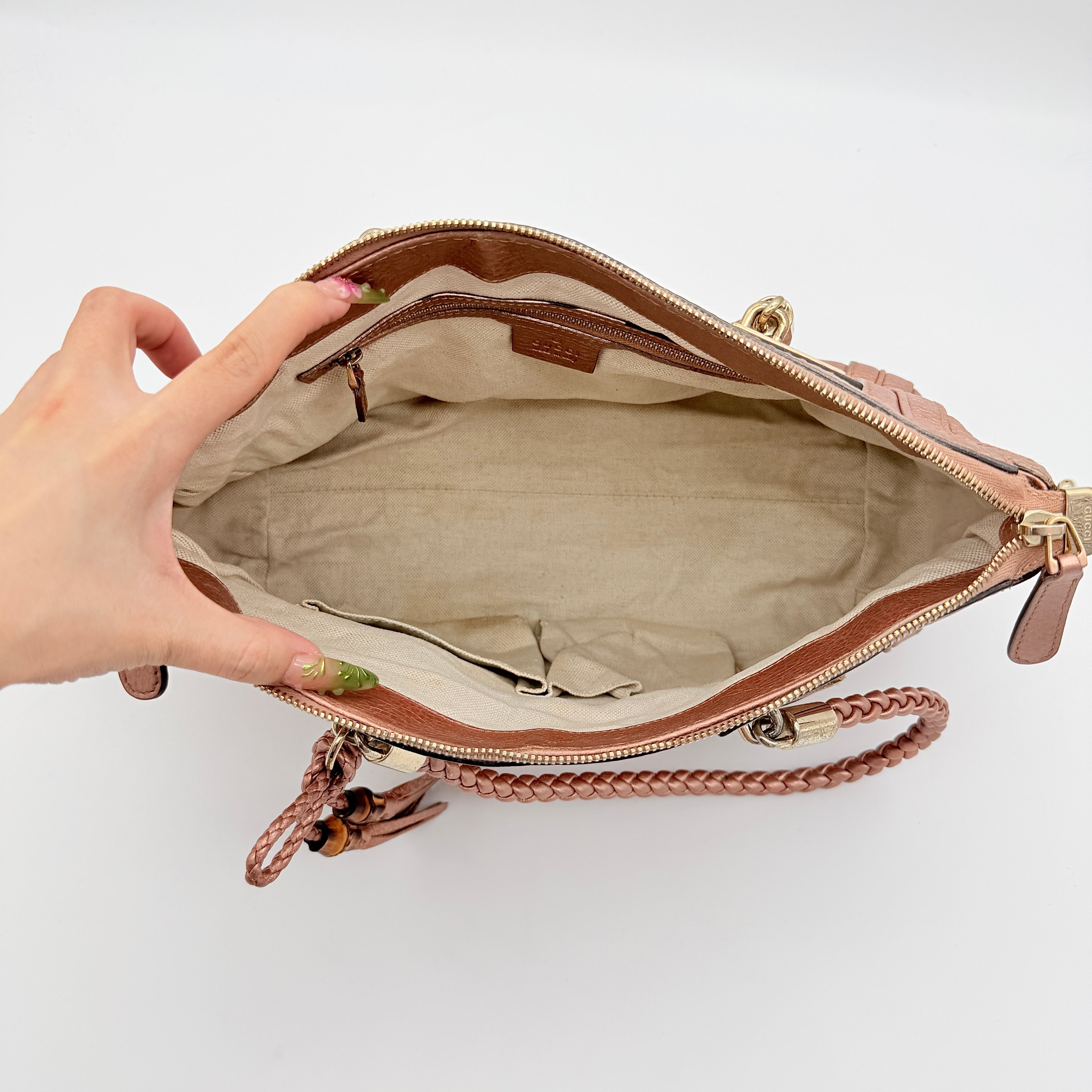 Gucci Bella Bamboo 2Way shoulder bag in metallic pink leather with braided handles and bamboo tassel accents, displayed with a detachable strap.
