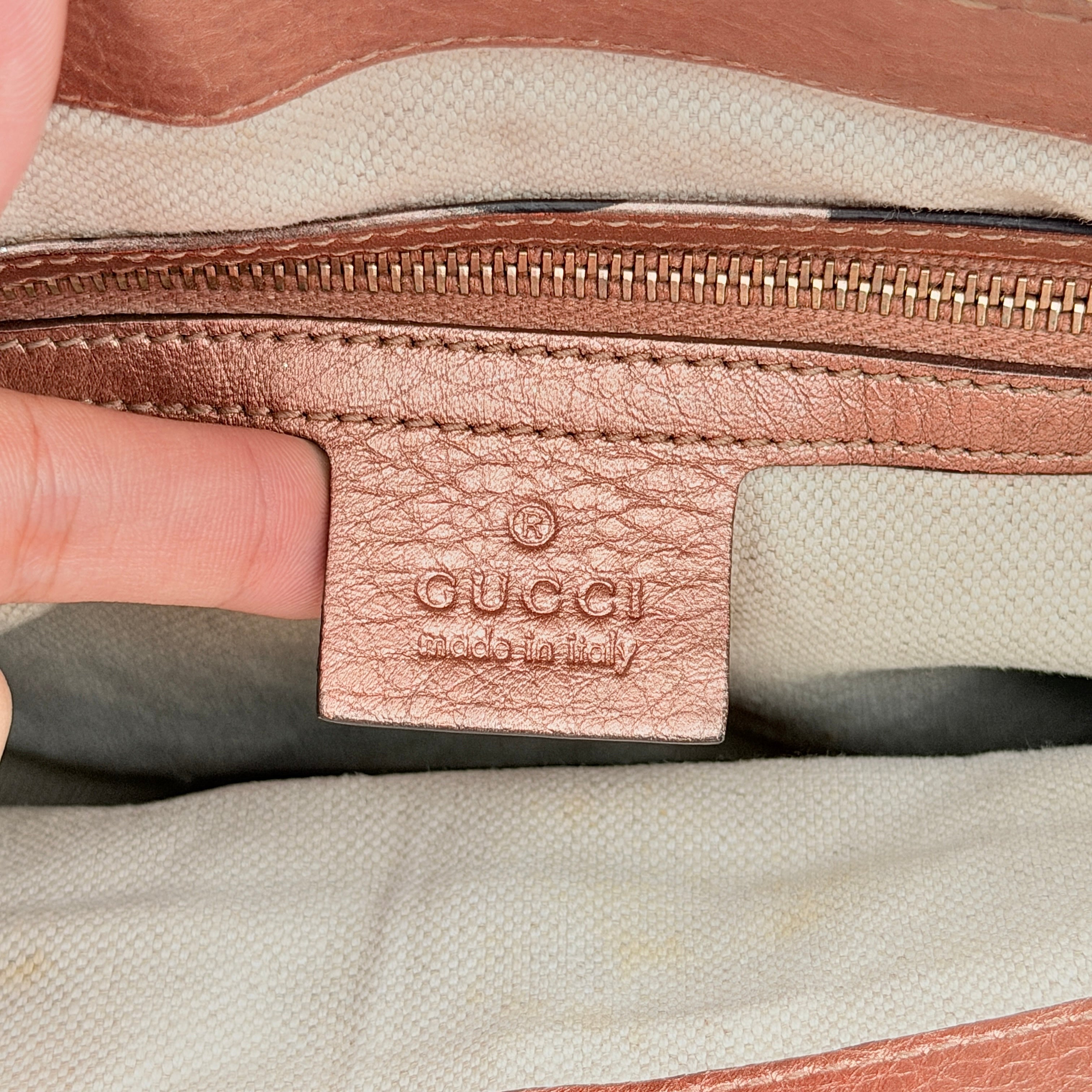 Gucci Bella Bamboo 2Way shoulder bag in metallic pink leather with braided handles and bamboo tassel accents, displayed with a detachable strap.
