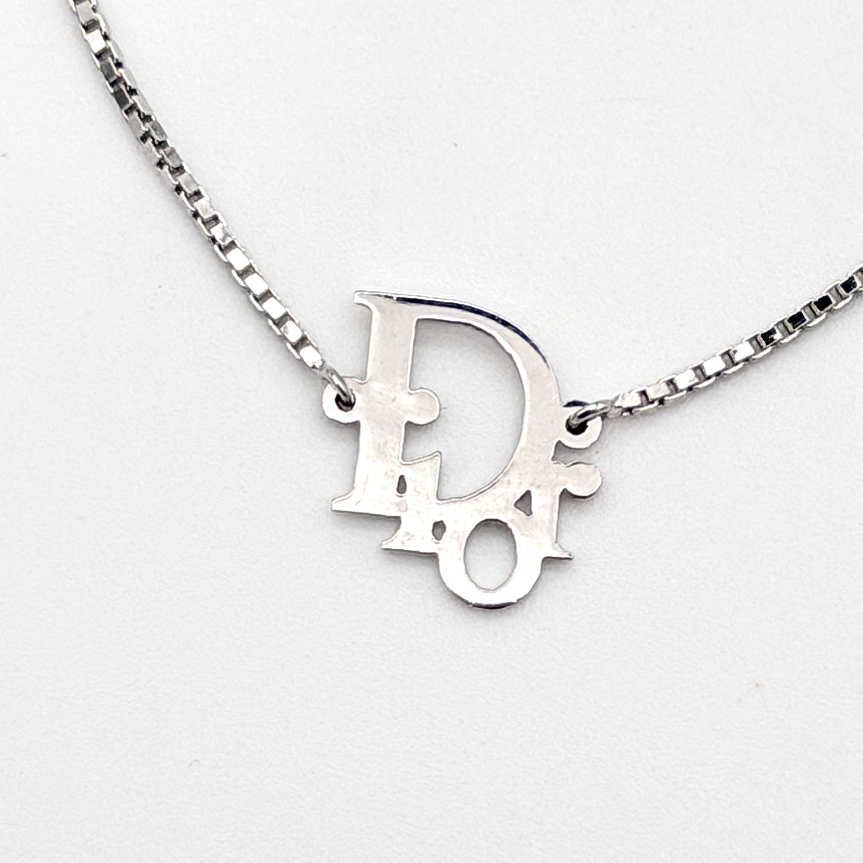 Dior silver logo bracelet with fine box chain and central branded charm photographed on a white background.