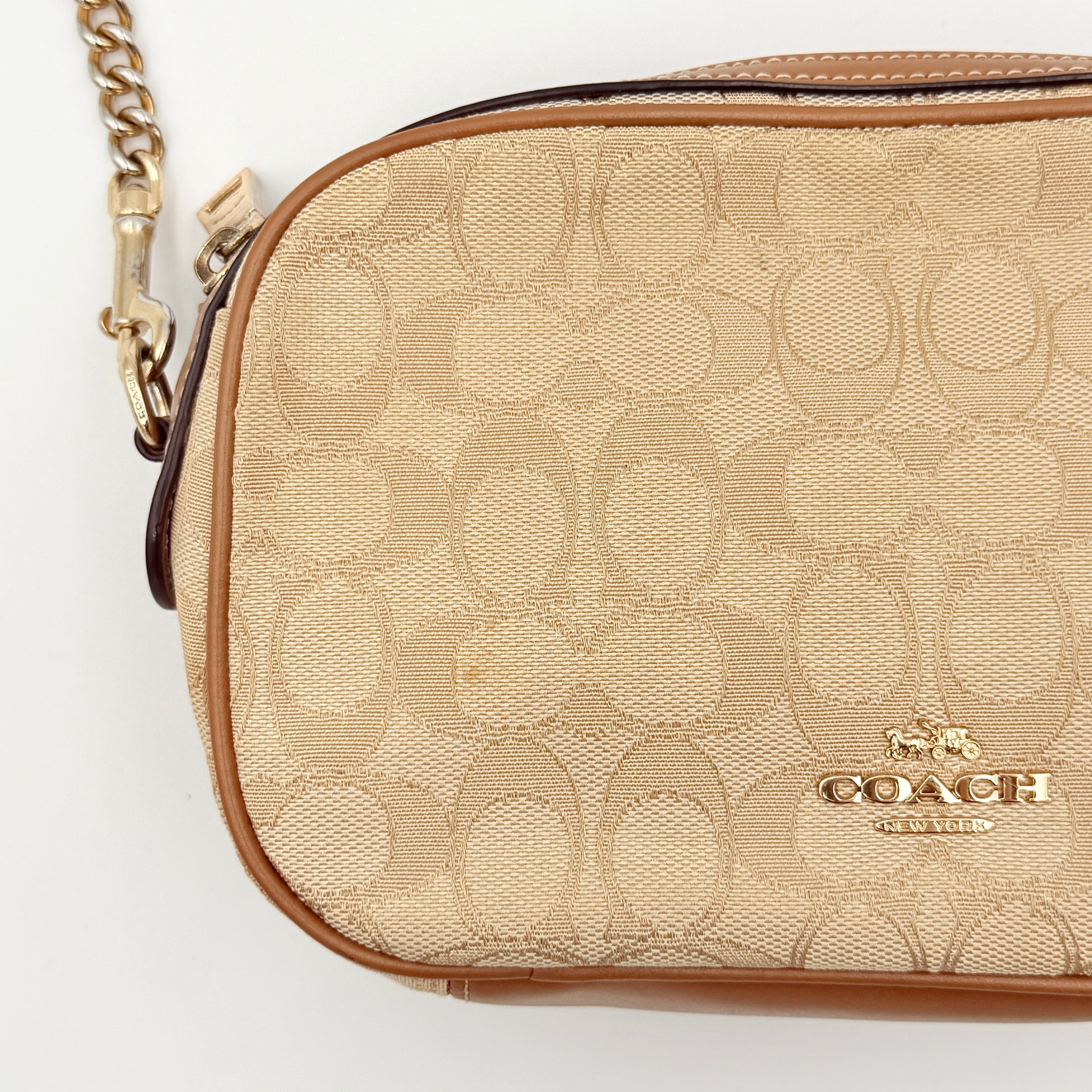 Coach Signature Isla Chain Crossbody Bag in beige and brown jacquard with caramel leather trim and gold-tone chain strap.