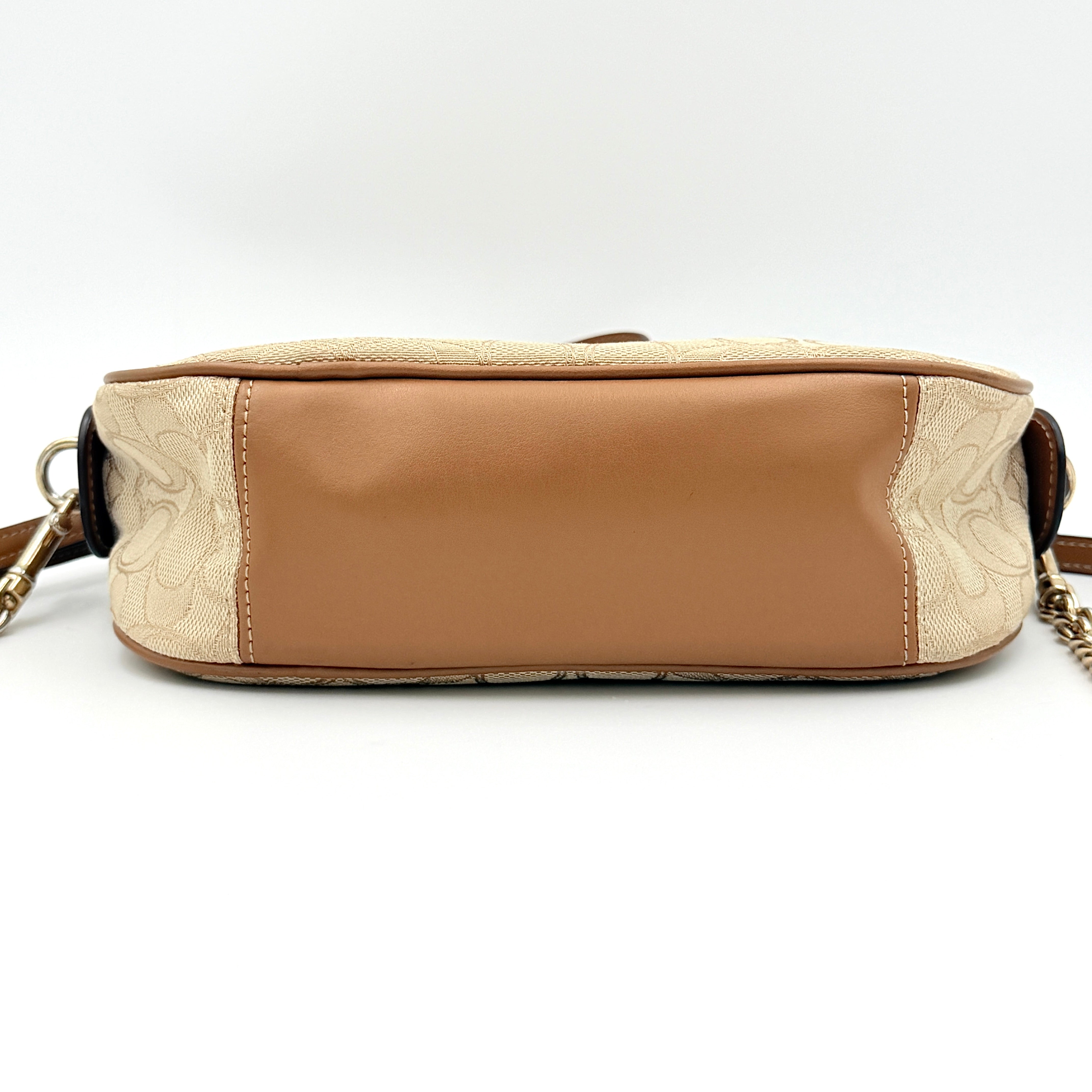Coach Signature Isla Chain Crossbody Bag in beige and brown jacquard with caramel leather trim and gold-tone chain strap.