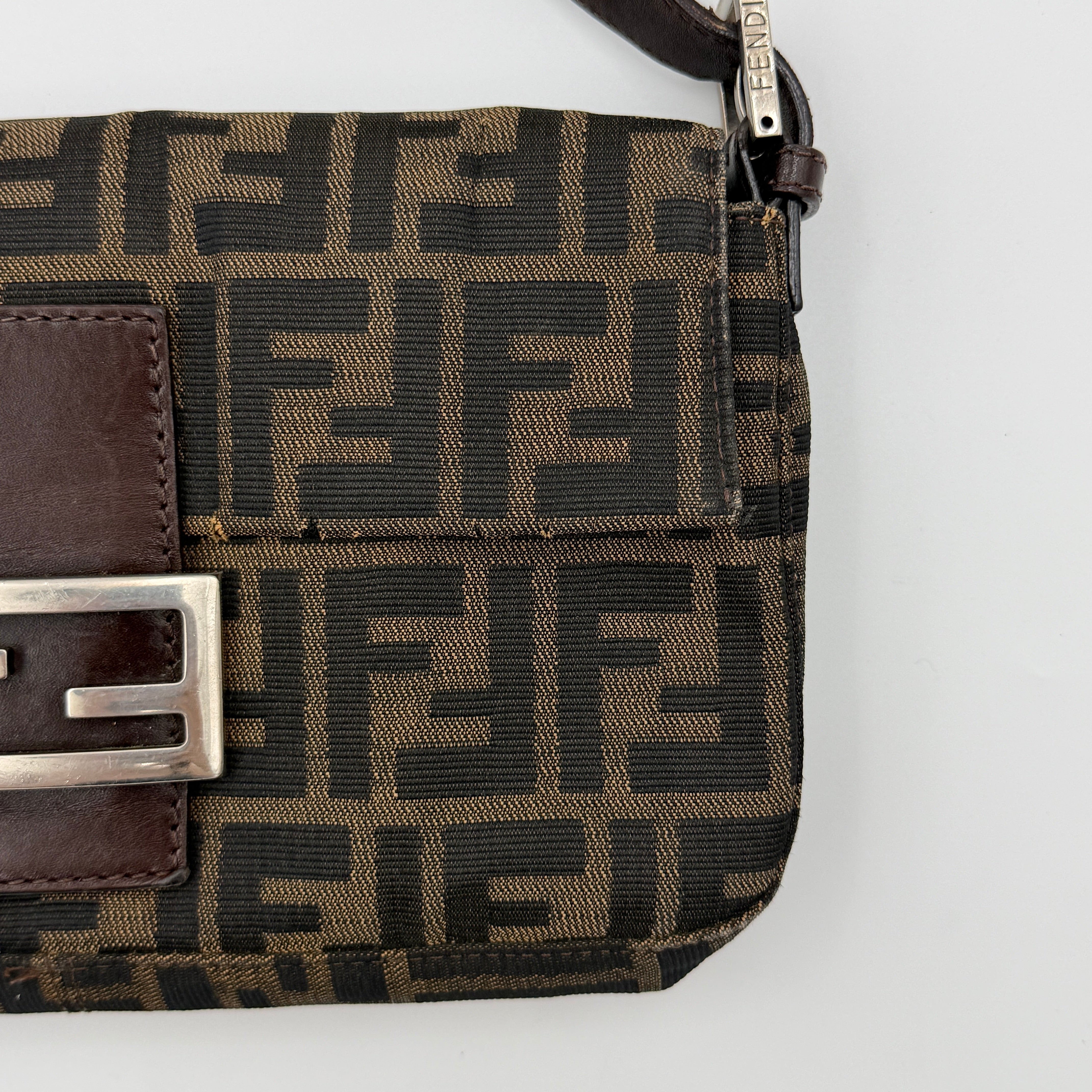 Fendi Zucca Print Baguette Bag in brown monogram canvas with silver-tone FF clasp and leather trim shown against a white background.