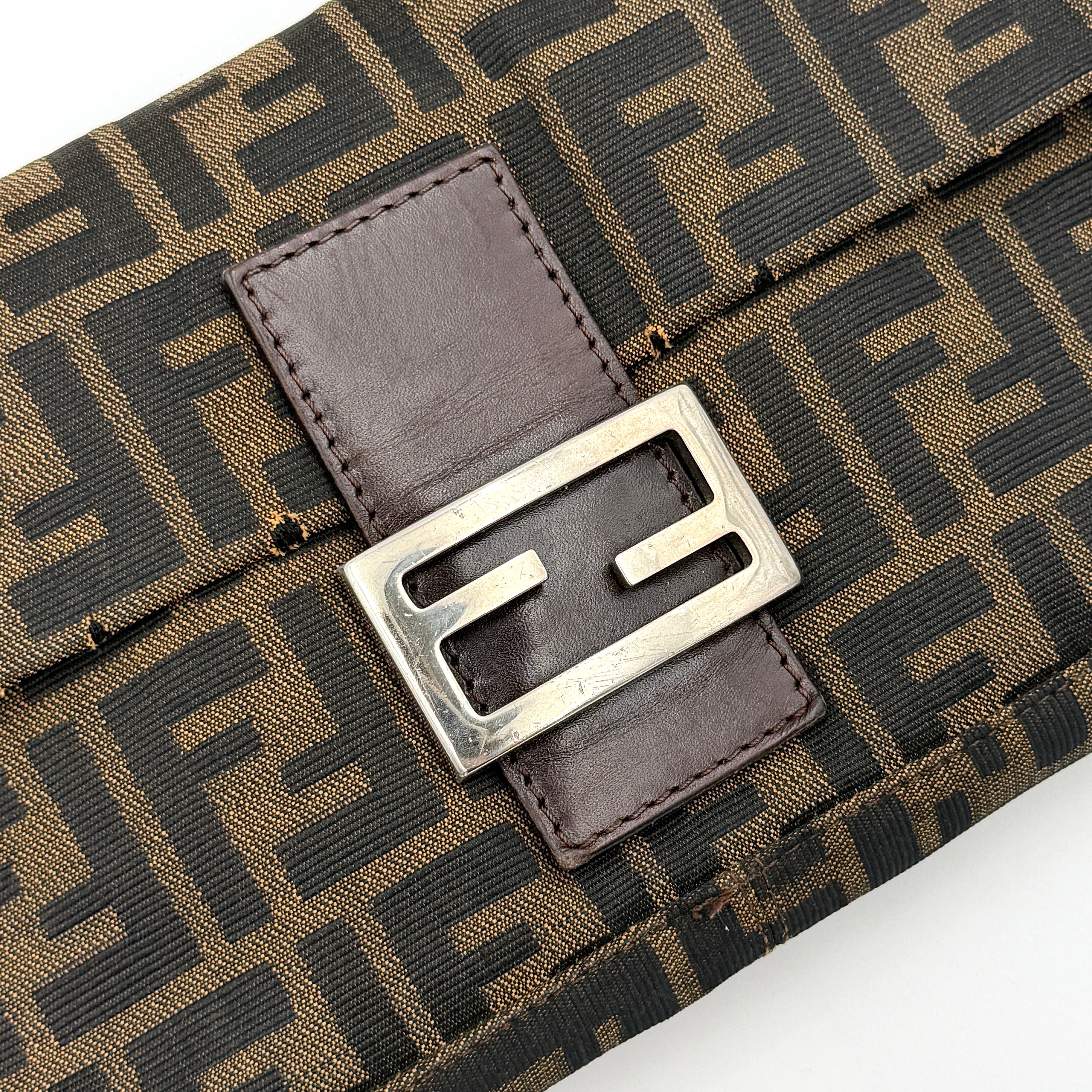 Fendi Zucca Print Baguette Bag in brown monogram canvas with silver-tone FF clasp and leather trim shown against a white background.