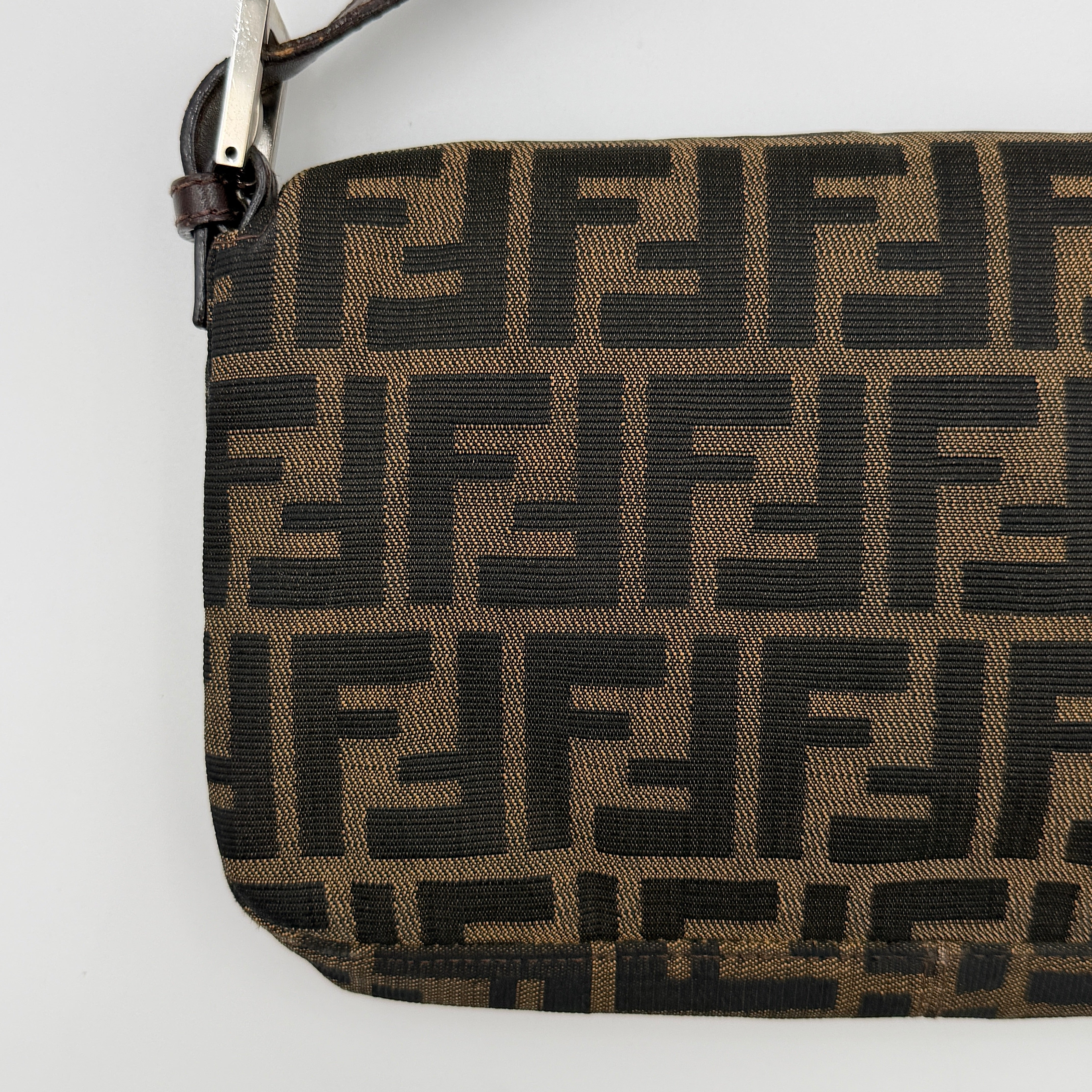 Fendi Zucca Print Baguette Bag in brown monogram canvas with silver-tone FF clasp and leather trim shown against a white background.