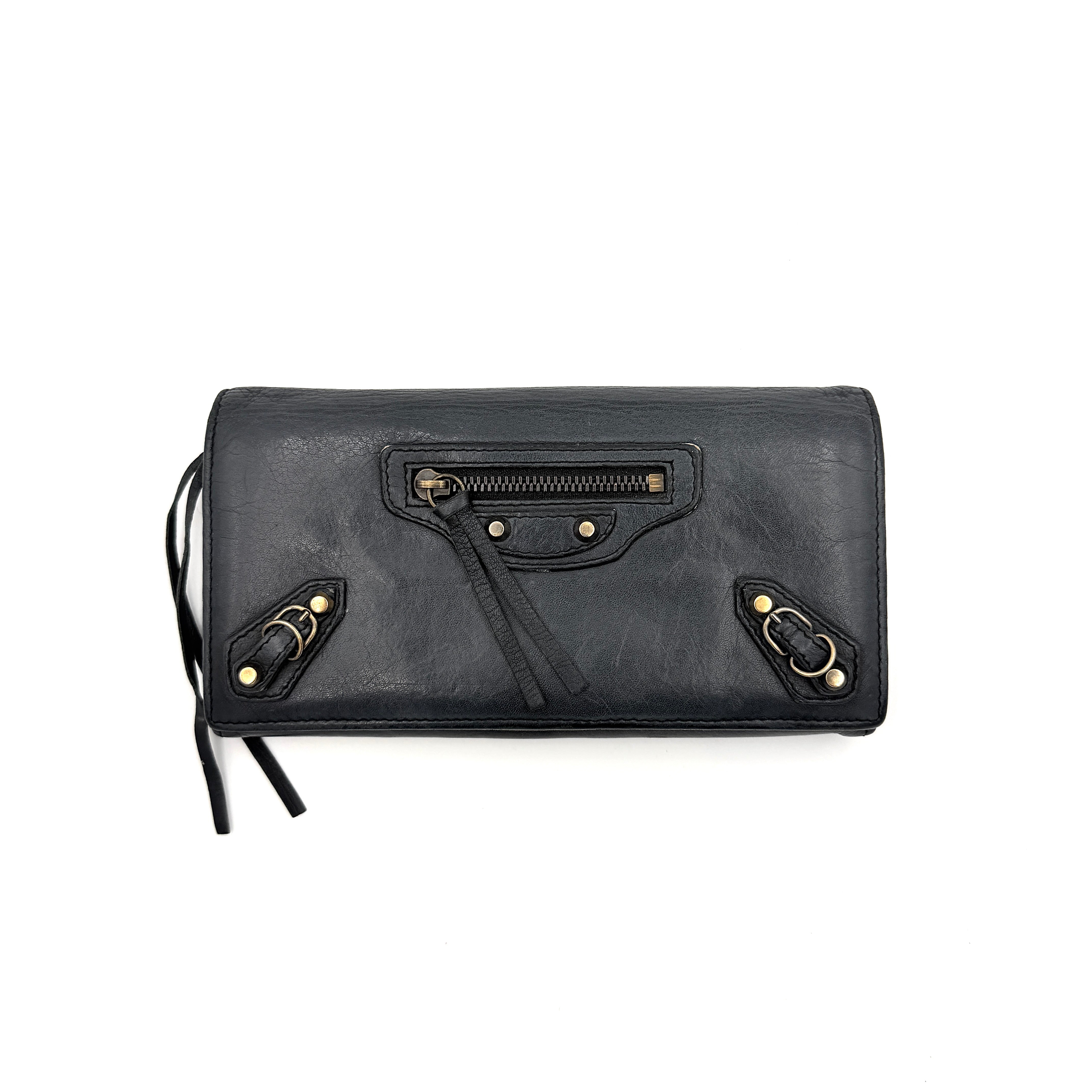 Balenciaga Agneau Leather Wallet in black with signature brass hardware and front zip detail, presented against a white background.