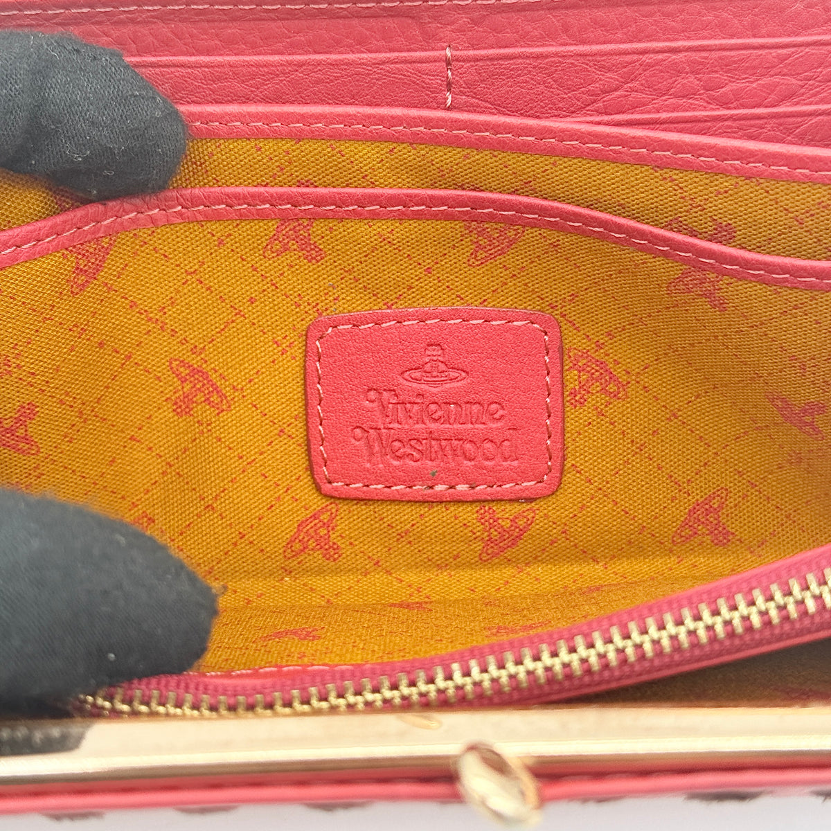 Vivienne Westwood Orb Perforated Kisslock Wallet in red leather with black whipstitch and gold-tone clasp shown on a white background.