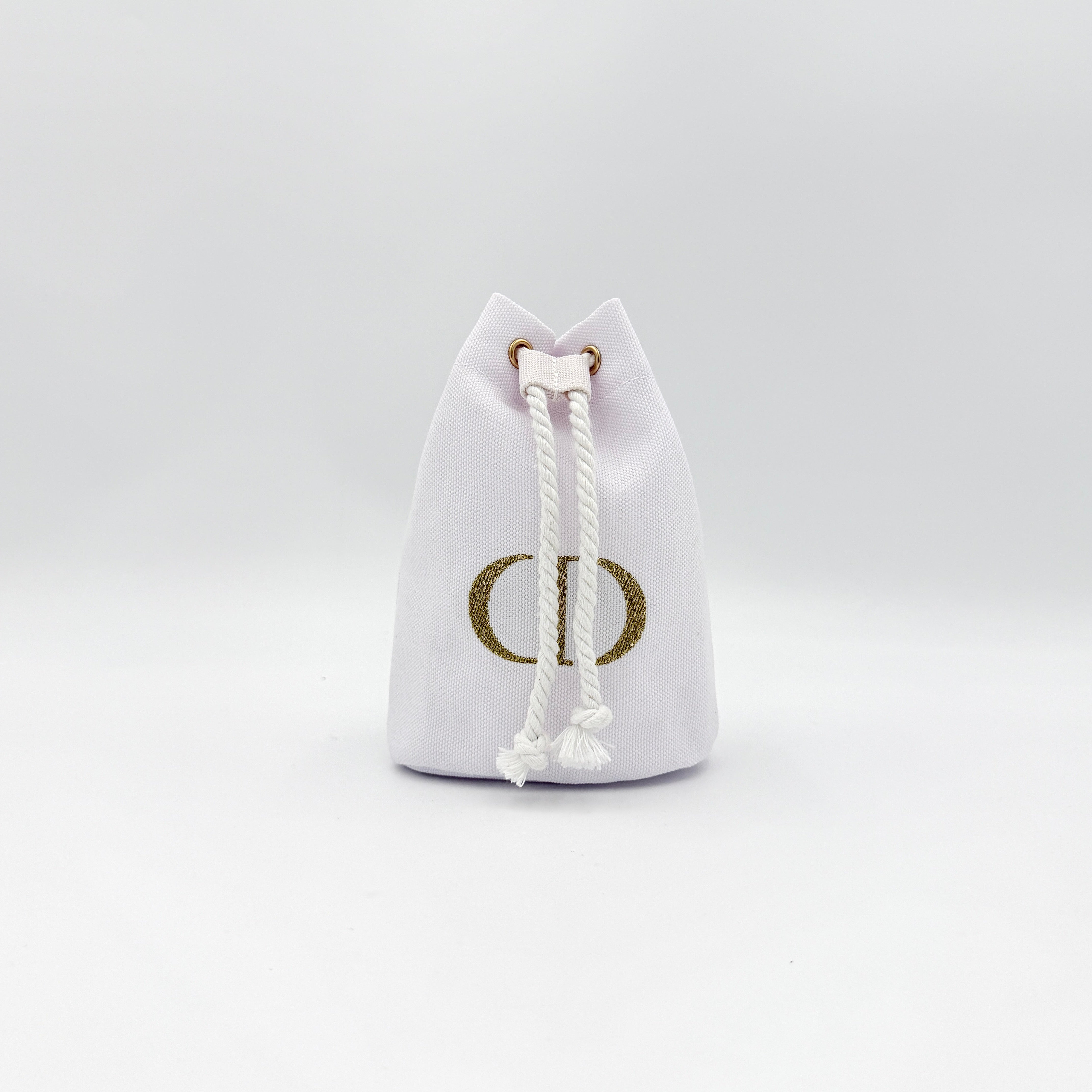 A structured white Dior drawstring pouch featuring a gold embroidered CD logo and white rope closure with gold-tone eyelets.