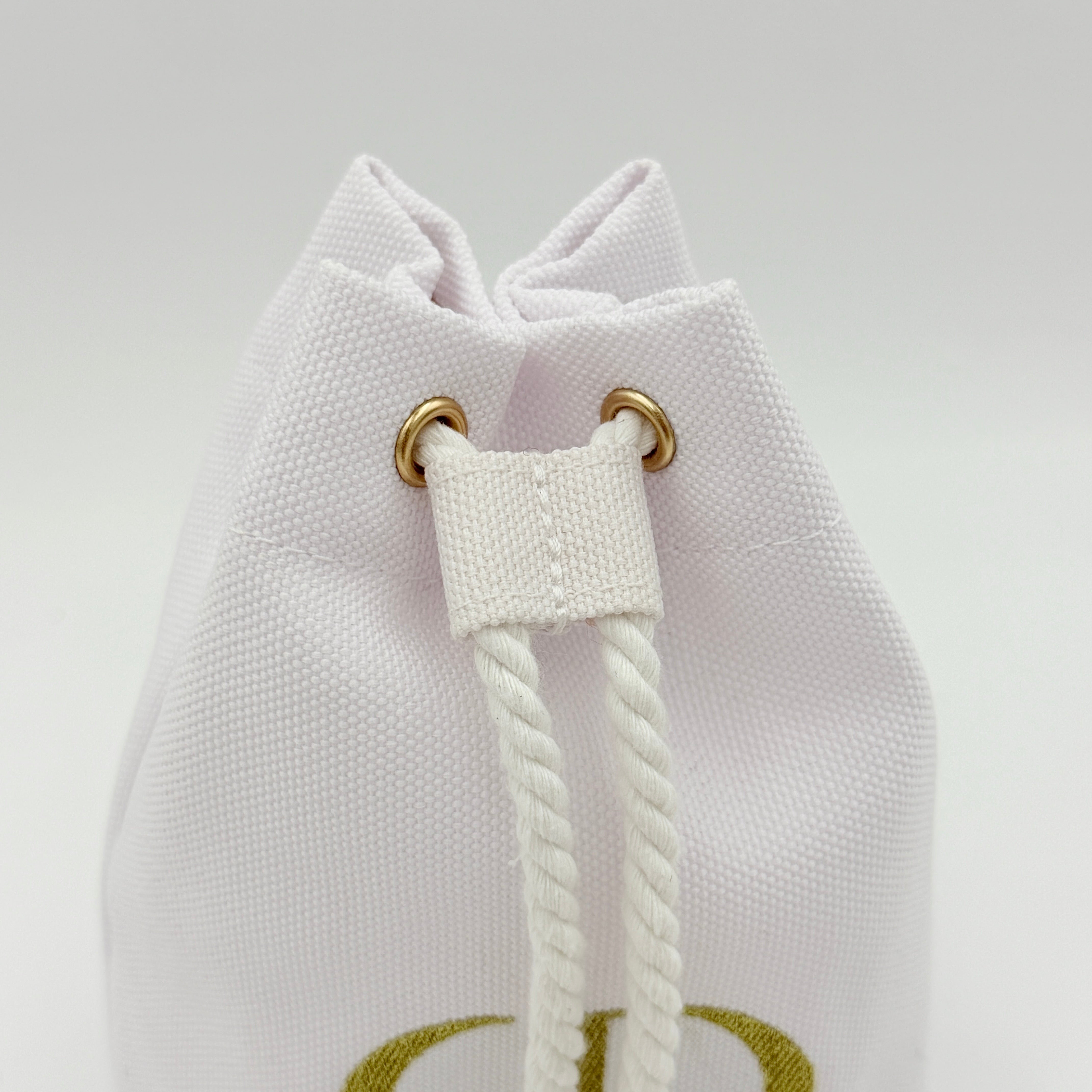 A structured white Dior drawstring pouch featuring a gold embroidered CD logo and white rope closure with gold-tone eyelets.