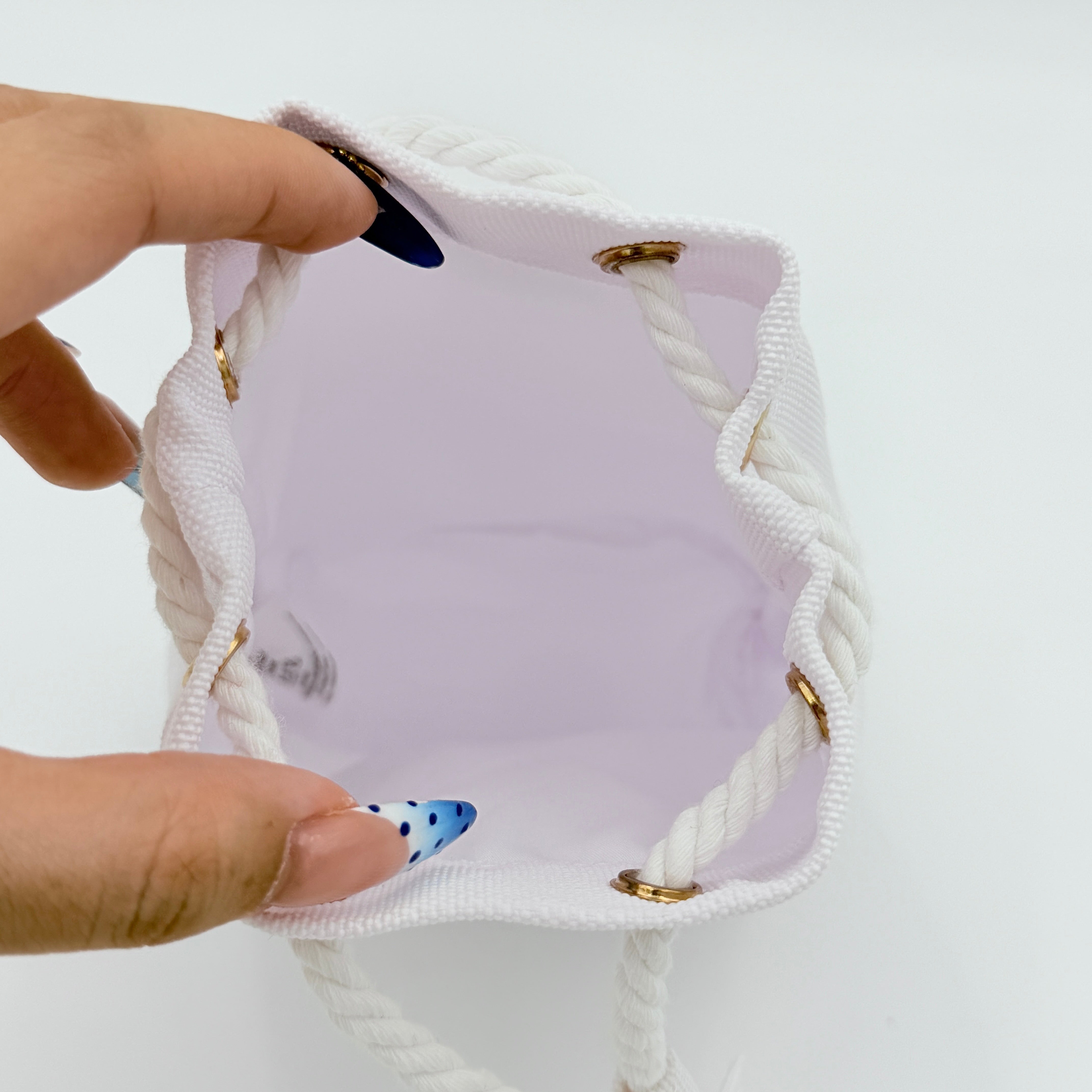 A structured white Dior drawstring pouch featuring a gold embroidered CD logo and white rope closure with gold-tone eyelets.