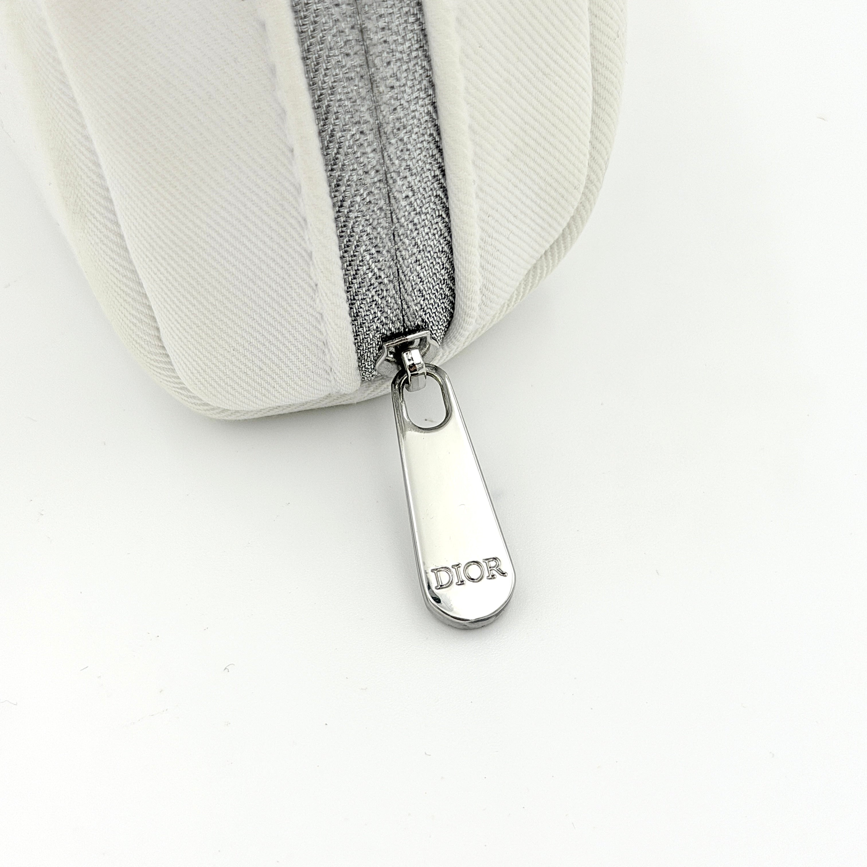 Crisp white Dior Beauty Logo Pouch with an embroidered logo and sleek silver-tone zipper, showcased against a minimalist backdrop.