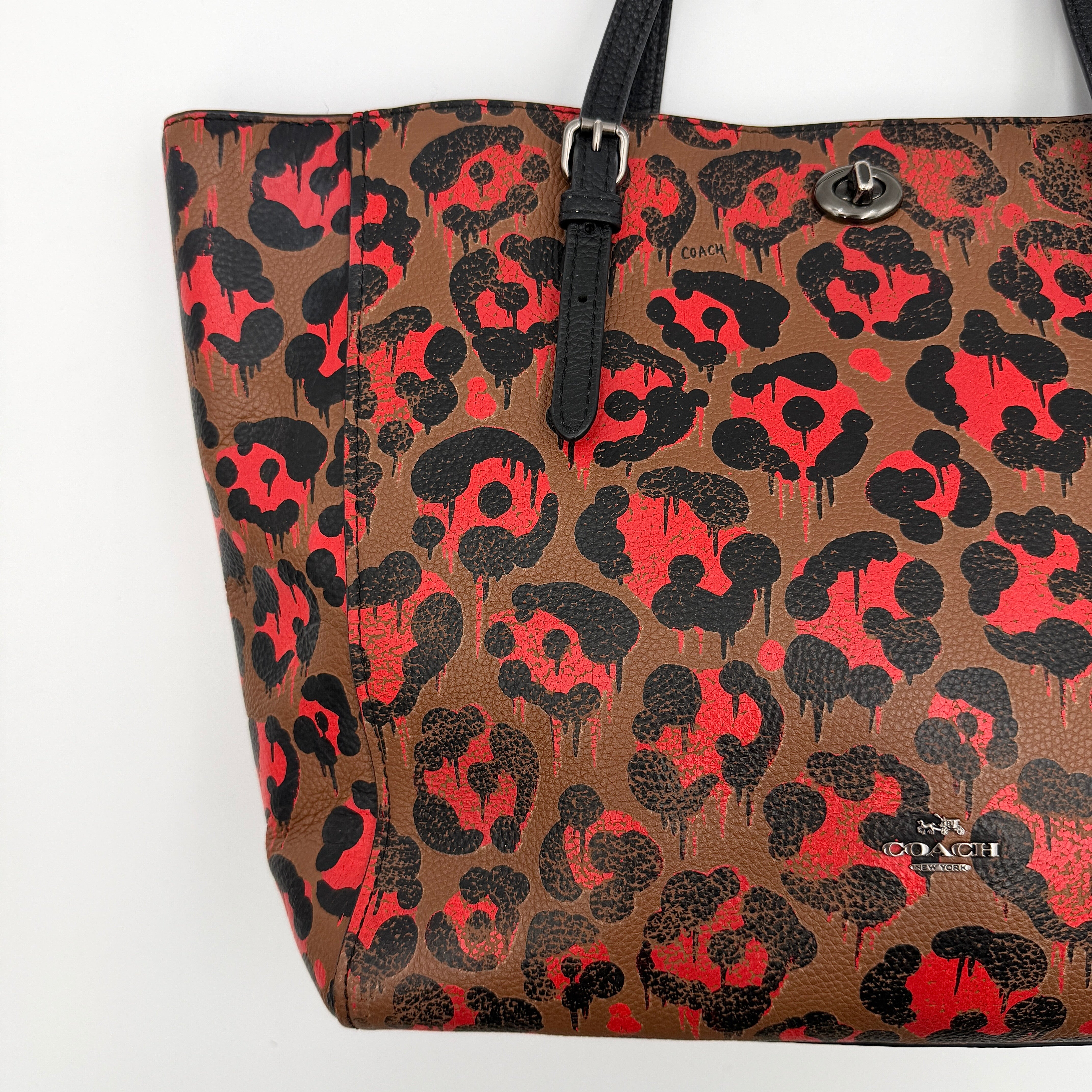 Coach City Tote in brown coated canvas, drenched in a vivid red and black leopard print, with black leather handles and silver hardware details.