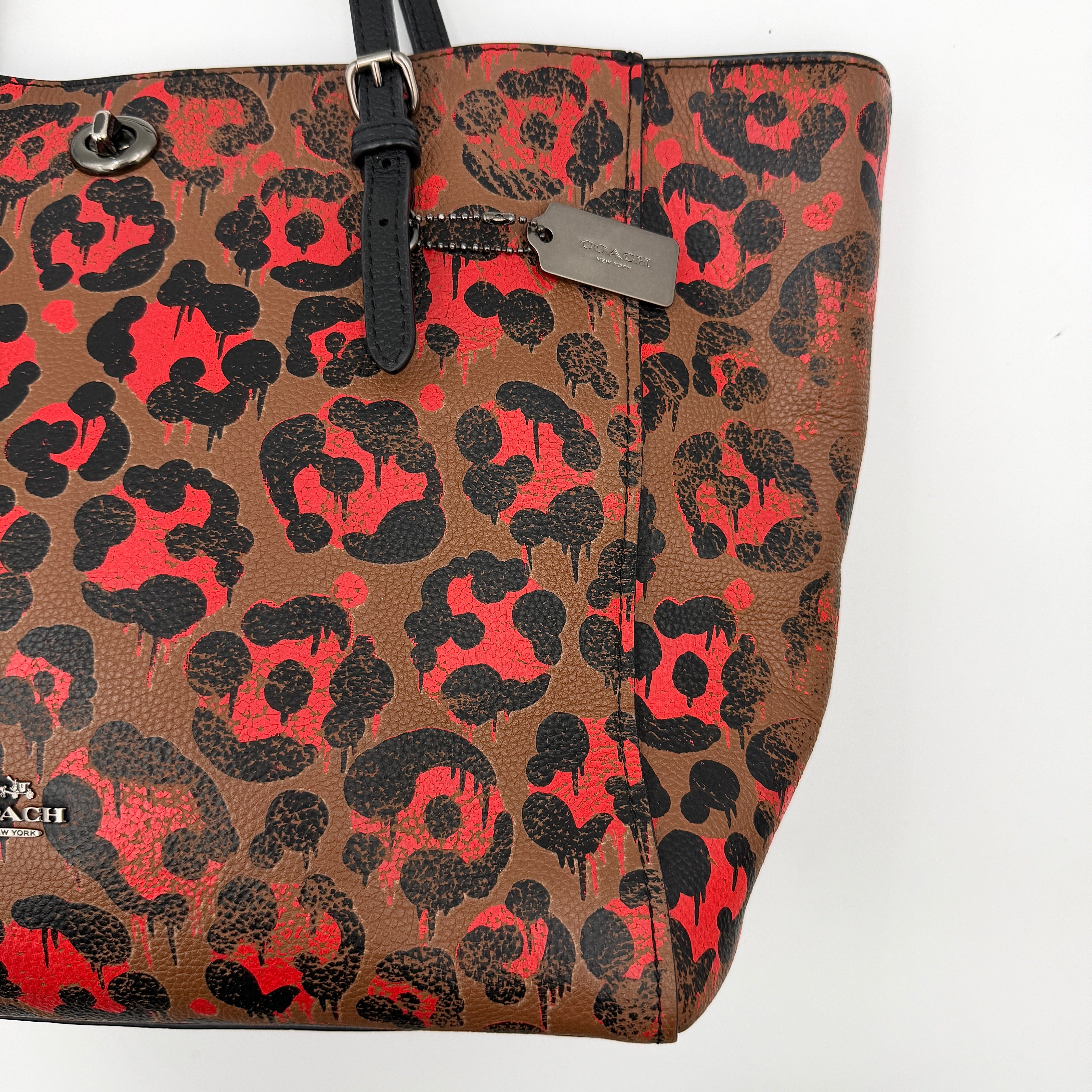Coach City Tote in brown coated canvas, drenched in a vivid red and black leopard print, with black leather handles and silver hardware details.