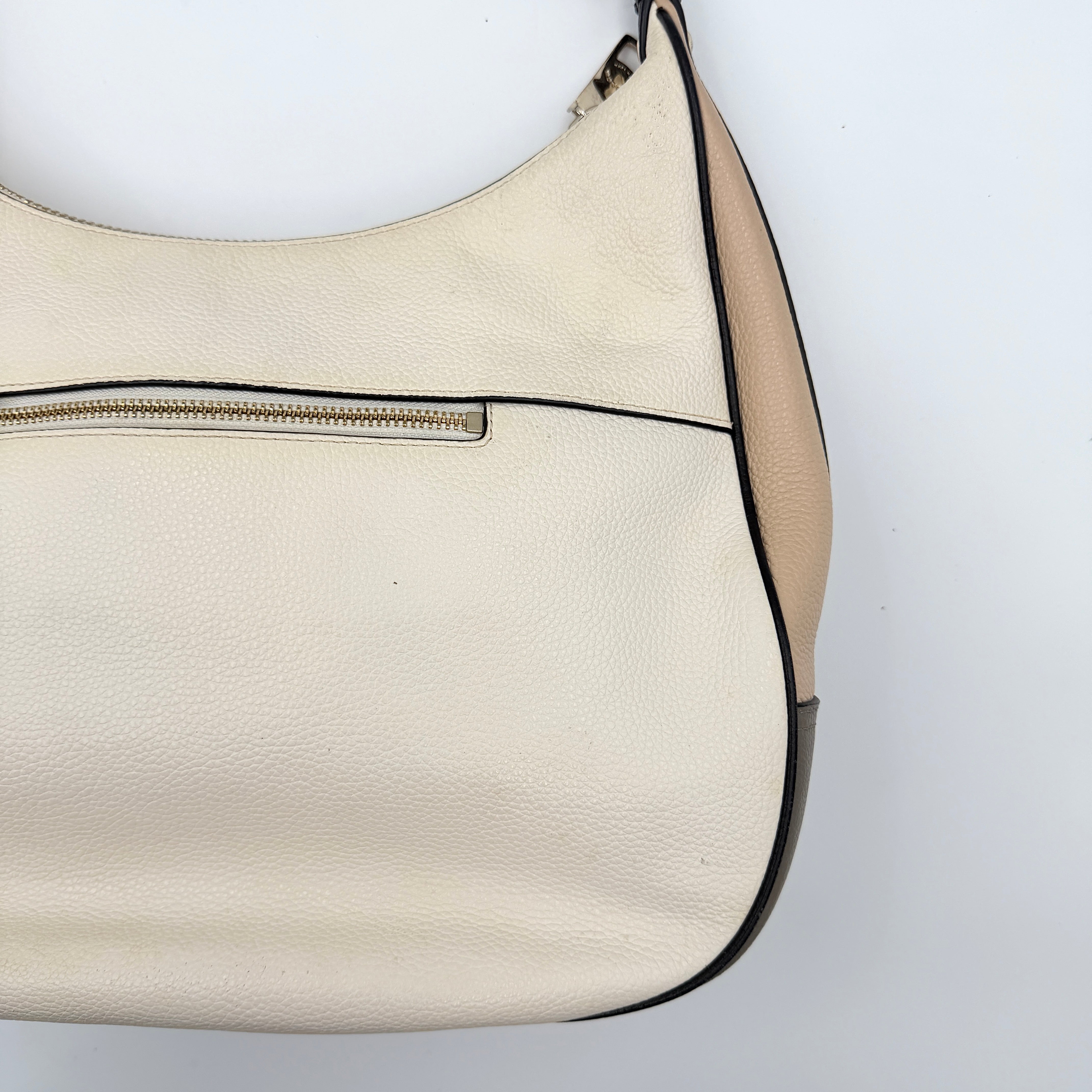Coach Harley East West Hobo in cream and beige pebbled leather with a sculpted silhouette, black piping, and silver hardware.