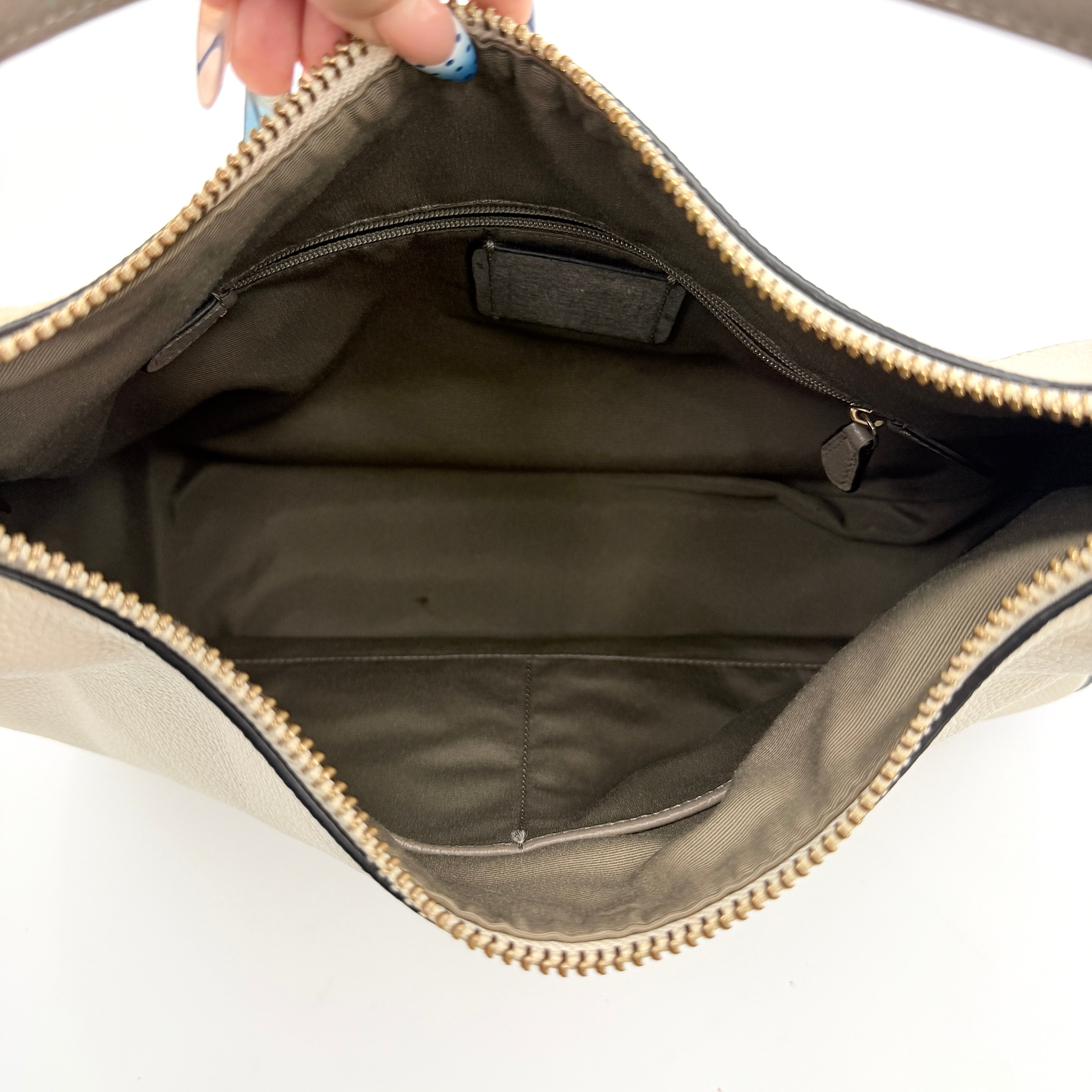 Coach Harley East West Hobo in cream and beige pebbled leather with a sculpted silhouette, black piping, and silver hardware.