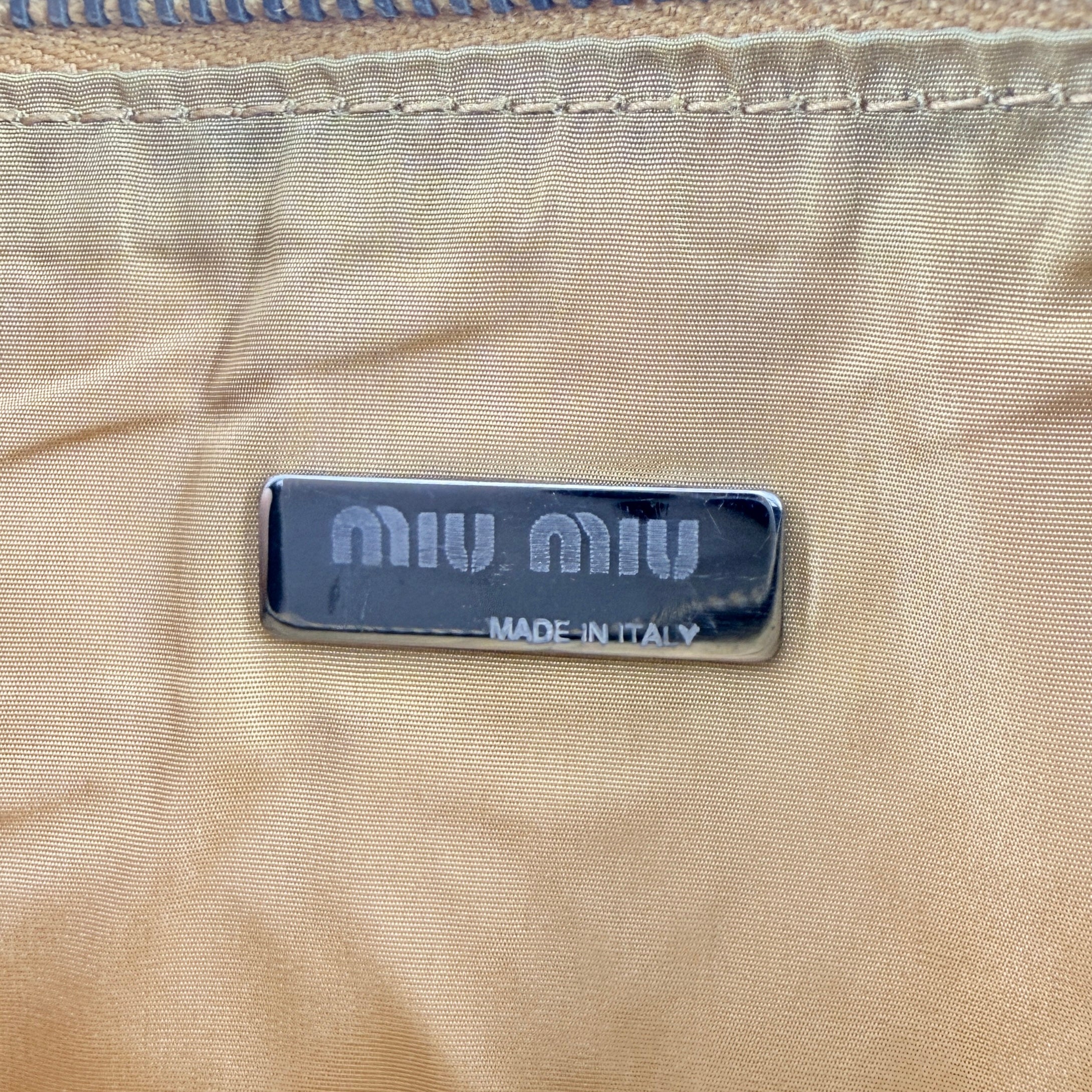 Miu Miu brown textured leather foldover pouch with matte black studs, zip closure, and slim silhouette.
