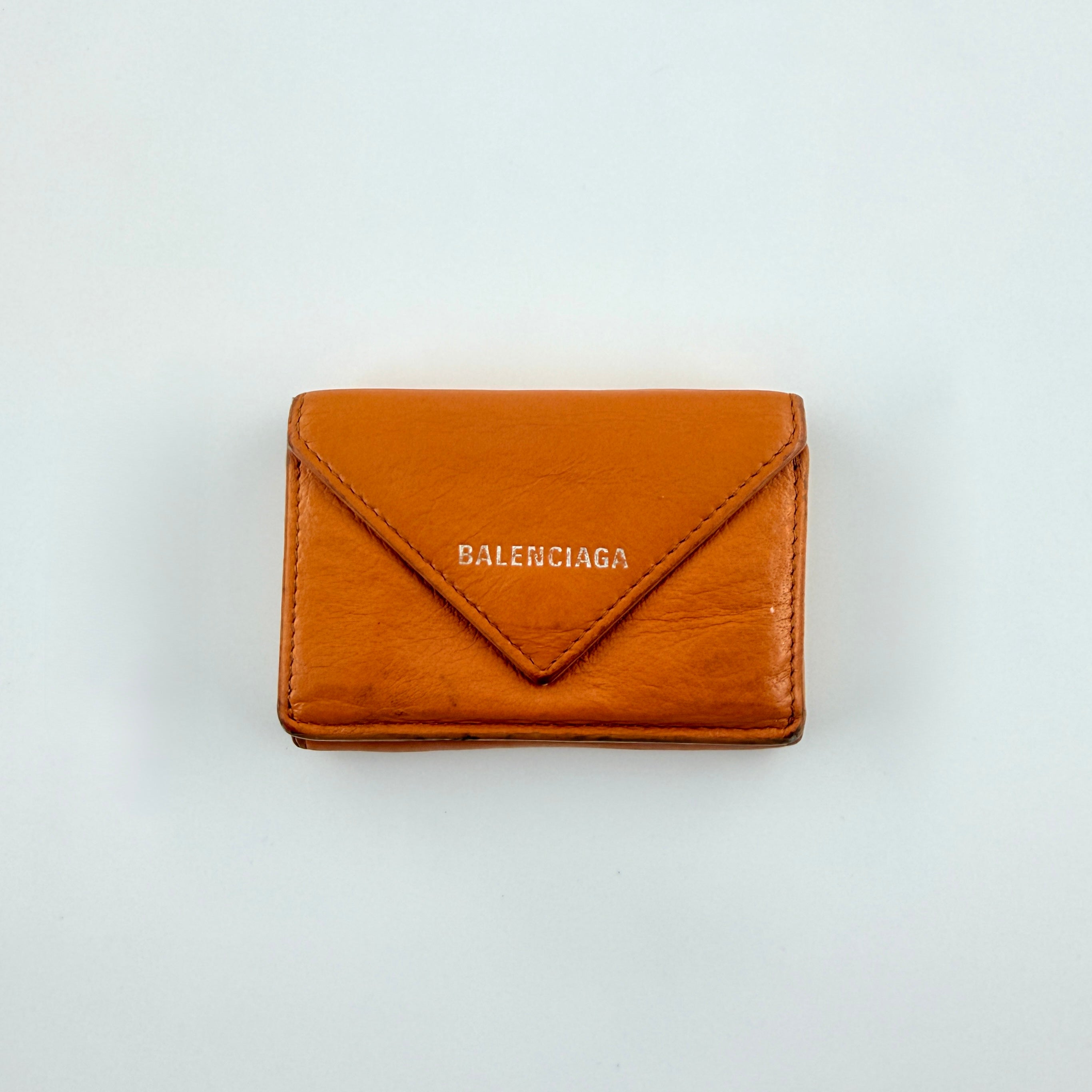 Balenciaga Papier Mini Wallet in vibrant orange grained leather, showcasing its envelope-style flap and silver logo detail.
