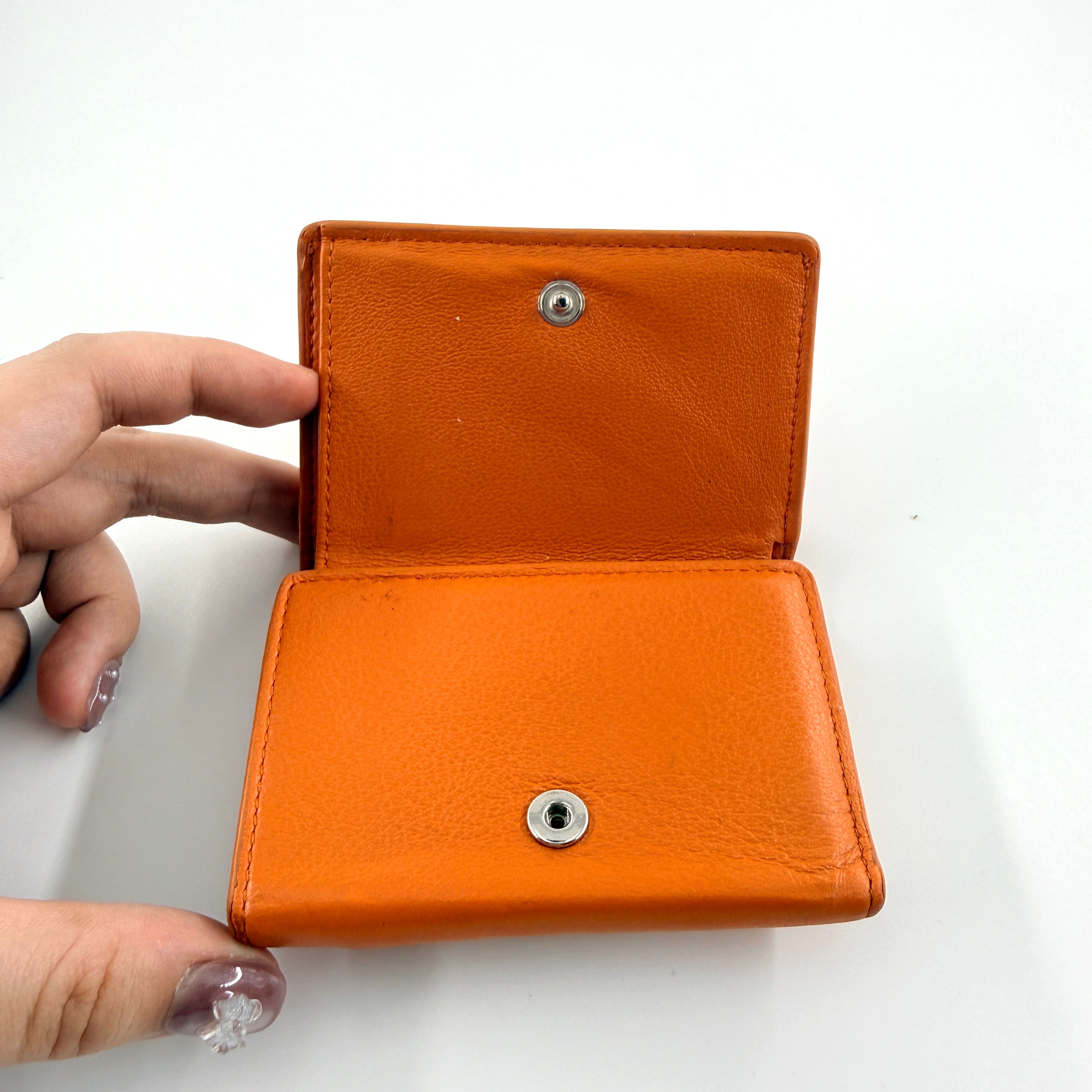 Balenciaga Papier Mini Wallet in vibrant orange grained leather, showcasing its envelope-style flap and silver logo detail.