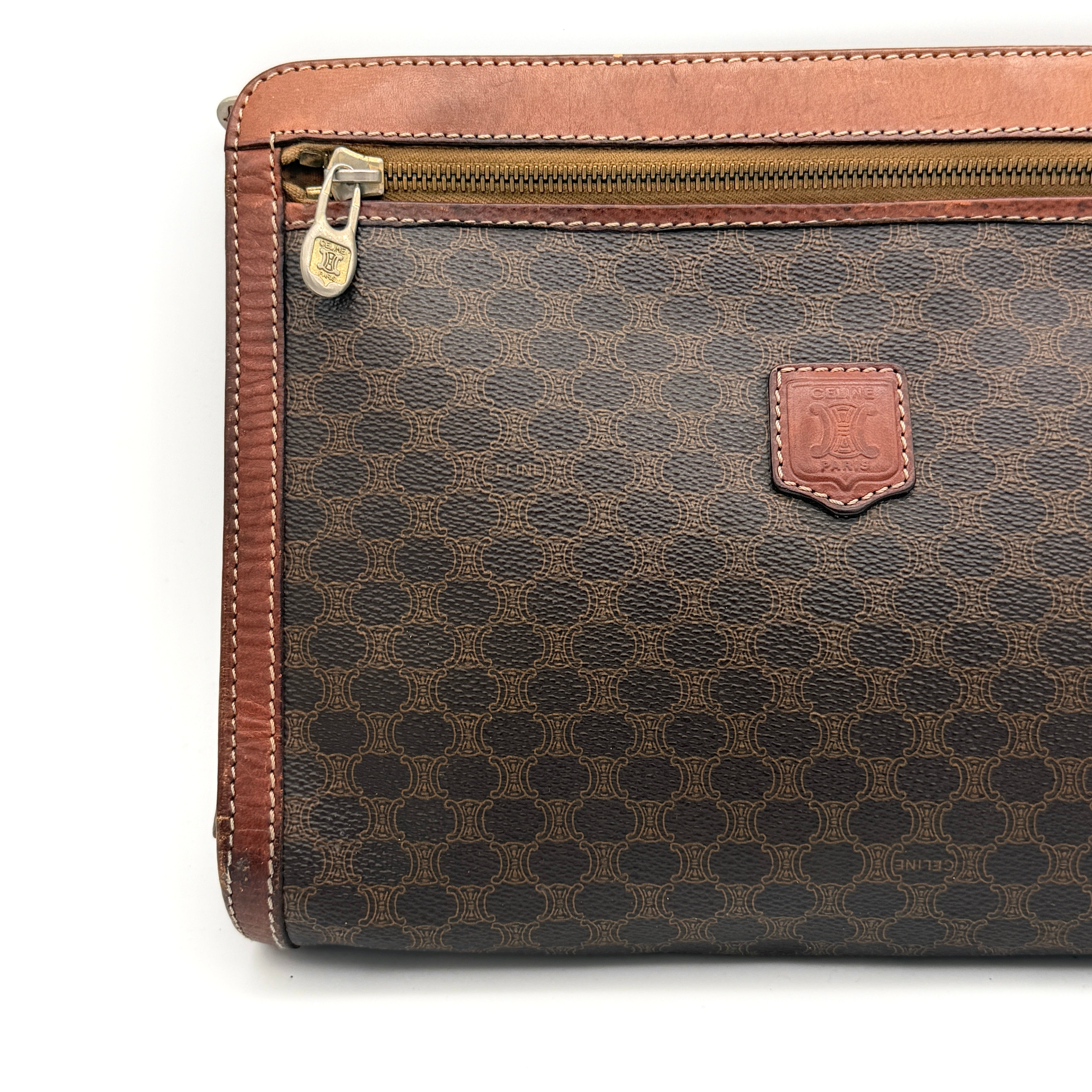 Front view of the Celine Triomphe Macadam clutch bag in brown canvas with tan leather trim and zip pocket.