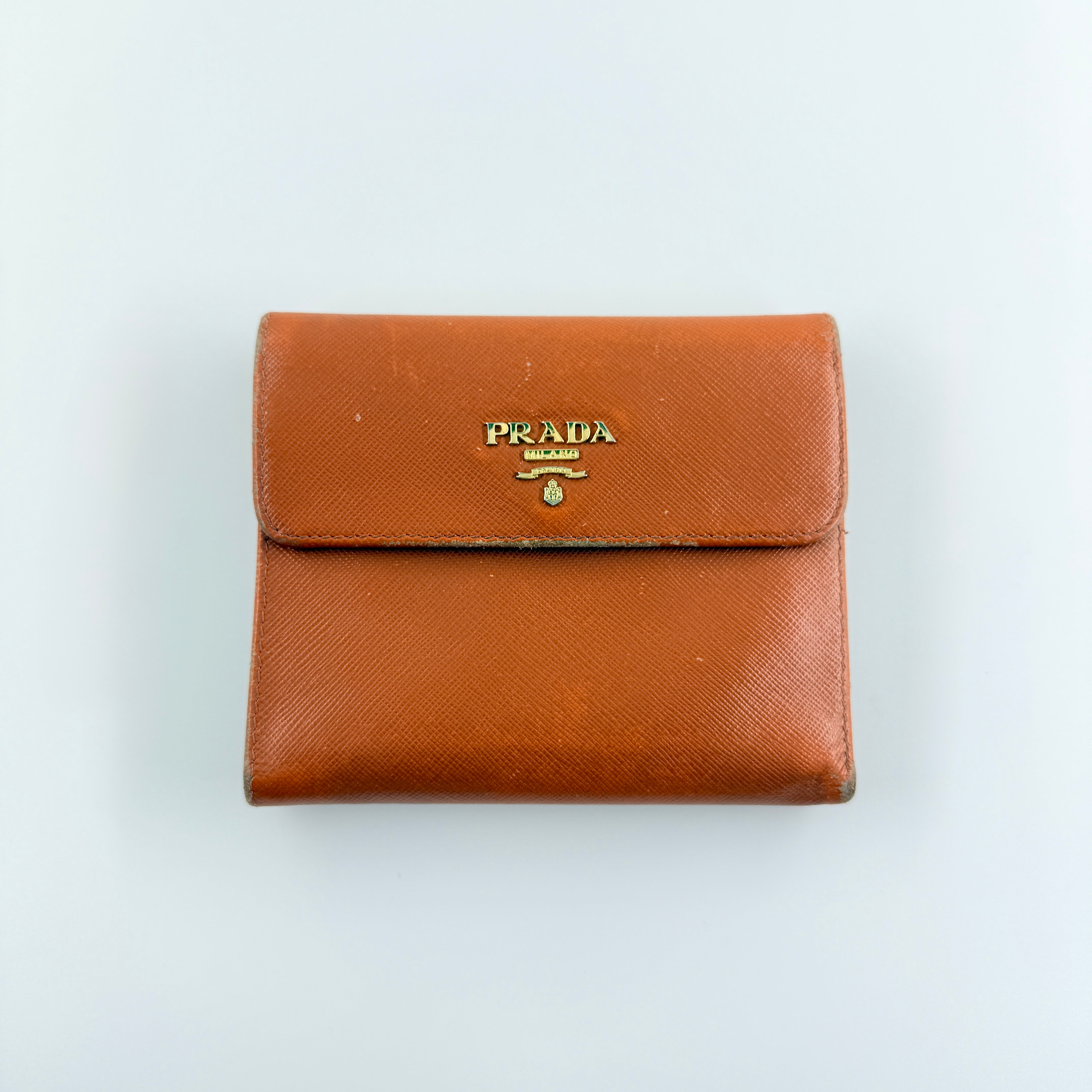 Prada Saffiano Leather Trifold Wallet in brown leather with gold-tone logo, showcasing its structured flap and crosshatch texture.