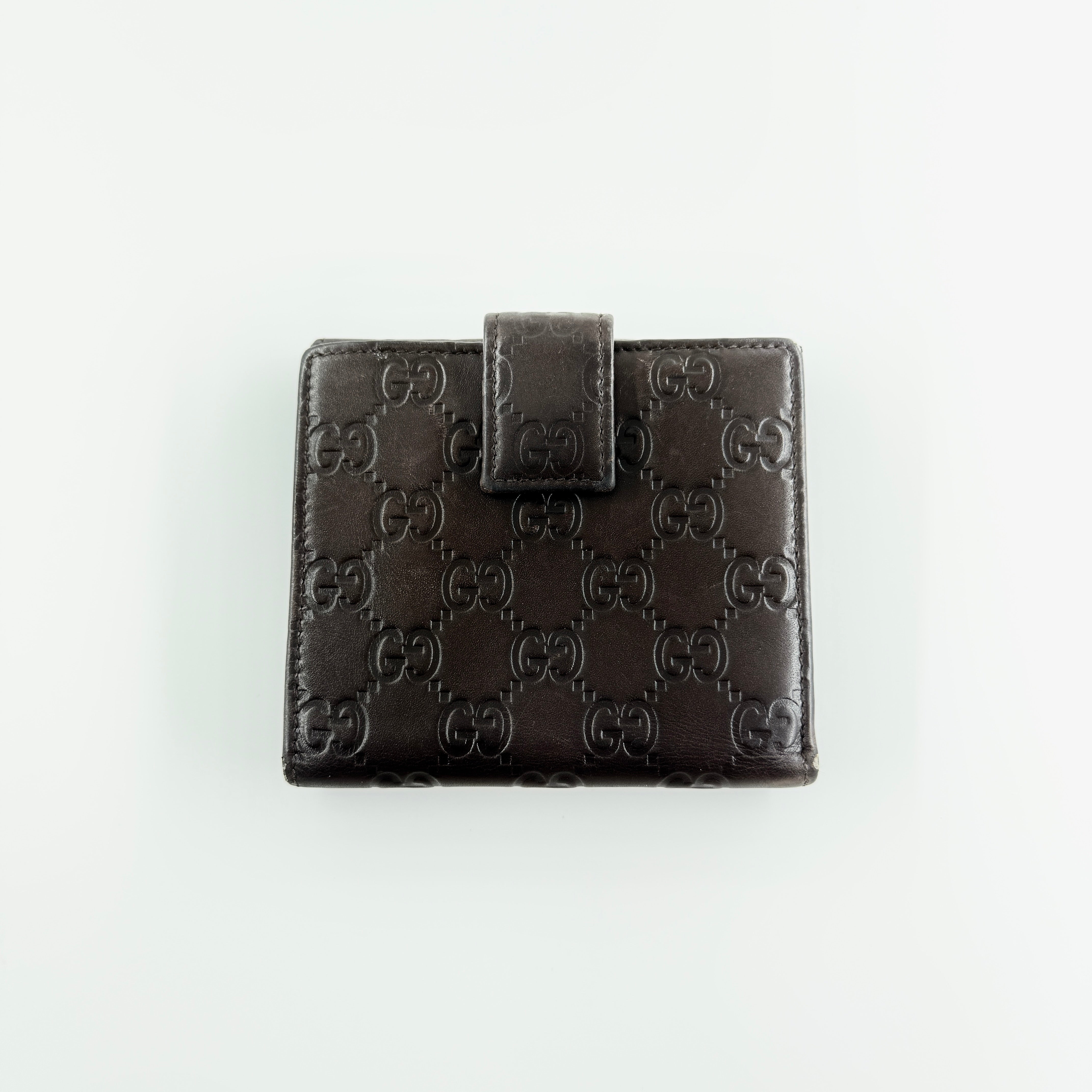 Front-facing Gucci GG Monogram Guccissima wallet in deep brown embossed leather with gold-tone bar accent.