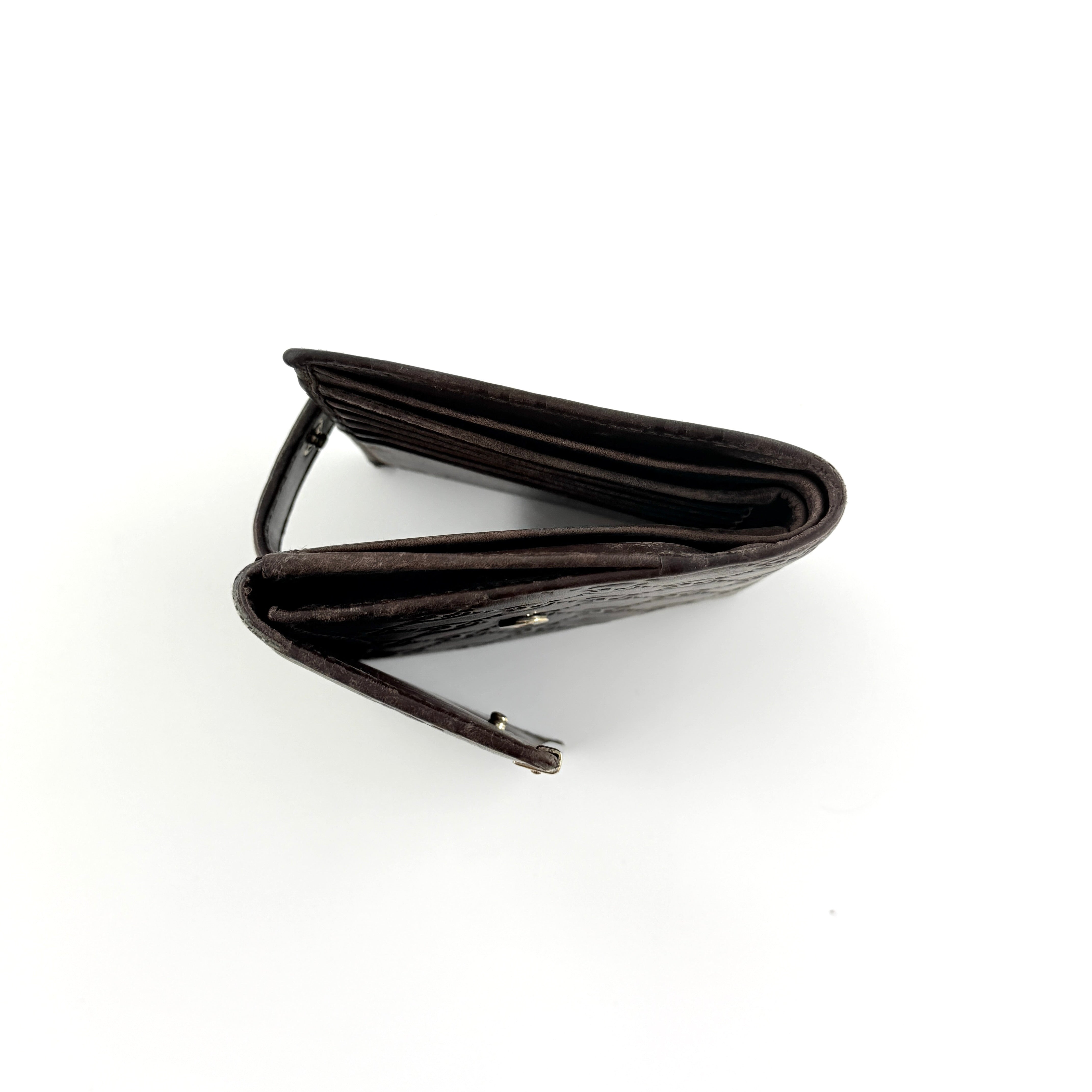 Front-facing Gucci GG Monogram Guccissima wallet in deep brown embossed leather with gold-tone bar accent.