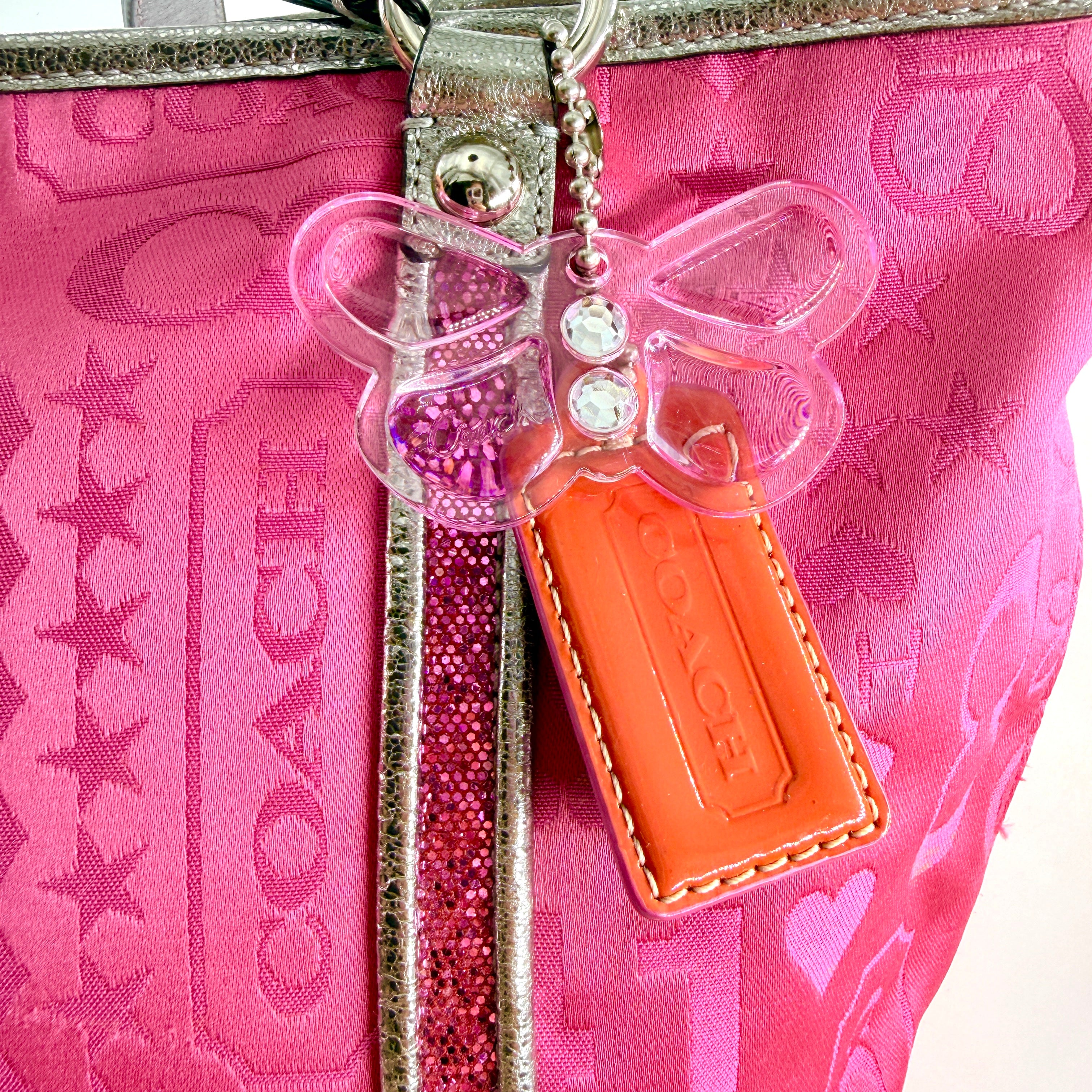 Coach Poppy Bandana Glitter Graffiti Tote Bag in vibrant pink with metallic silver handles, adorned with glitter accents and butterfly charm.