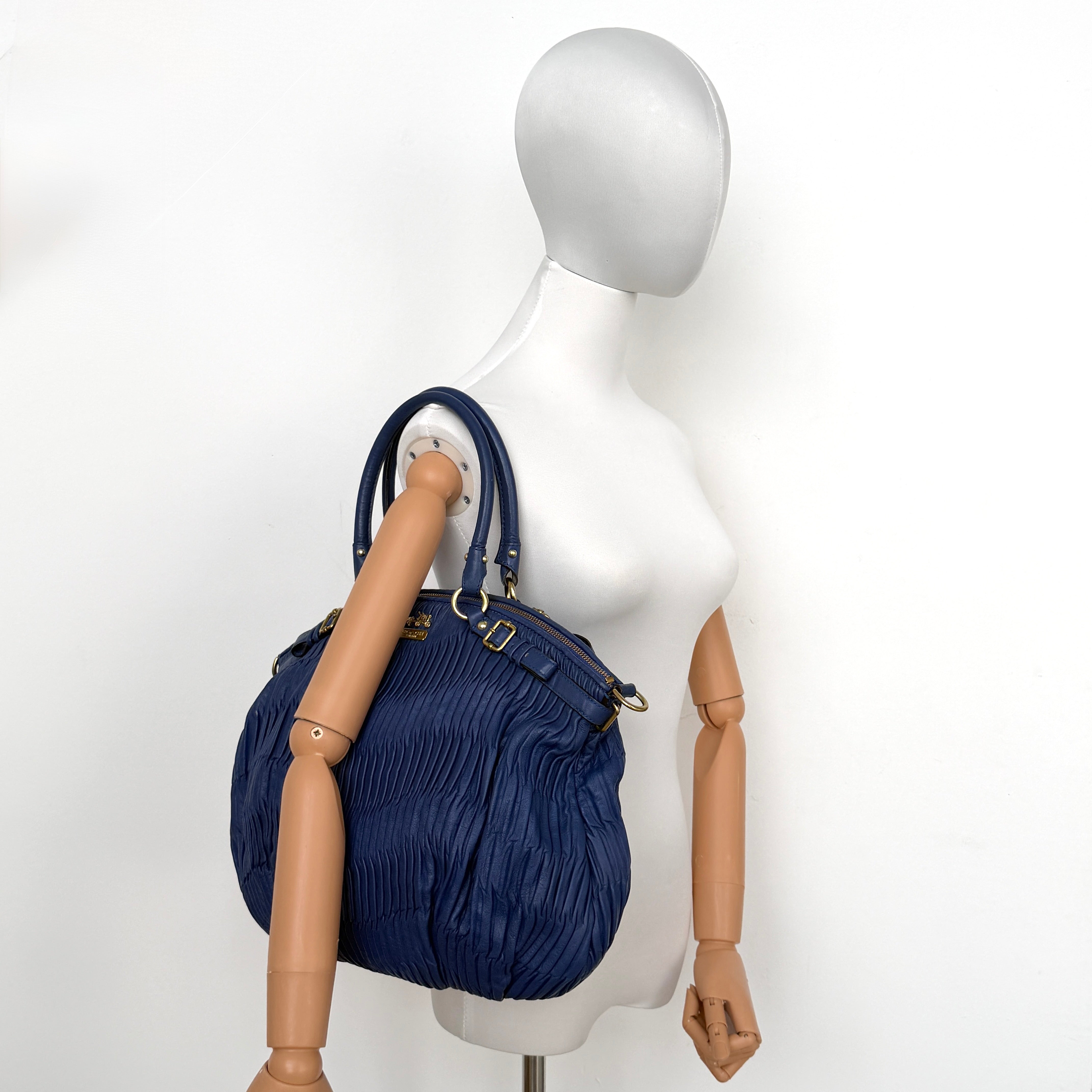 Coach Madison Shoulder Bag in gathered blue leather with gold-tone hardware and removable shoulder strap displayed against a white backdrop.