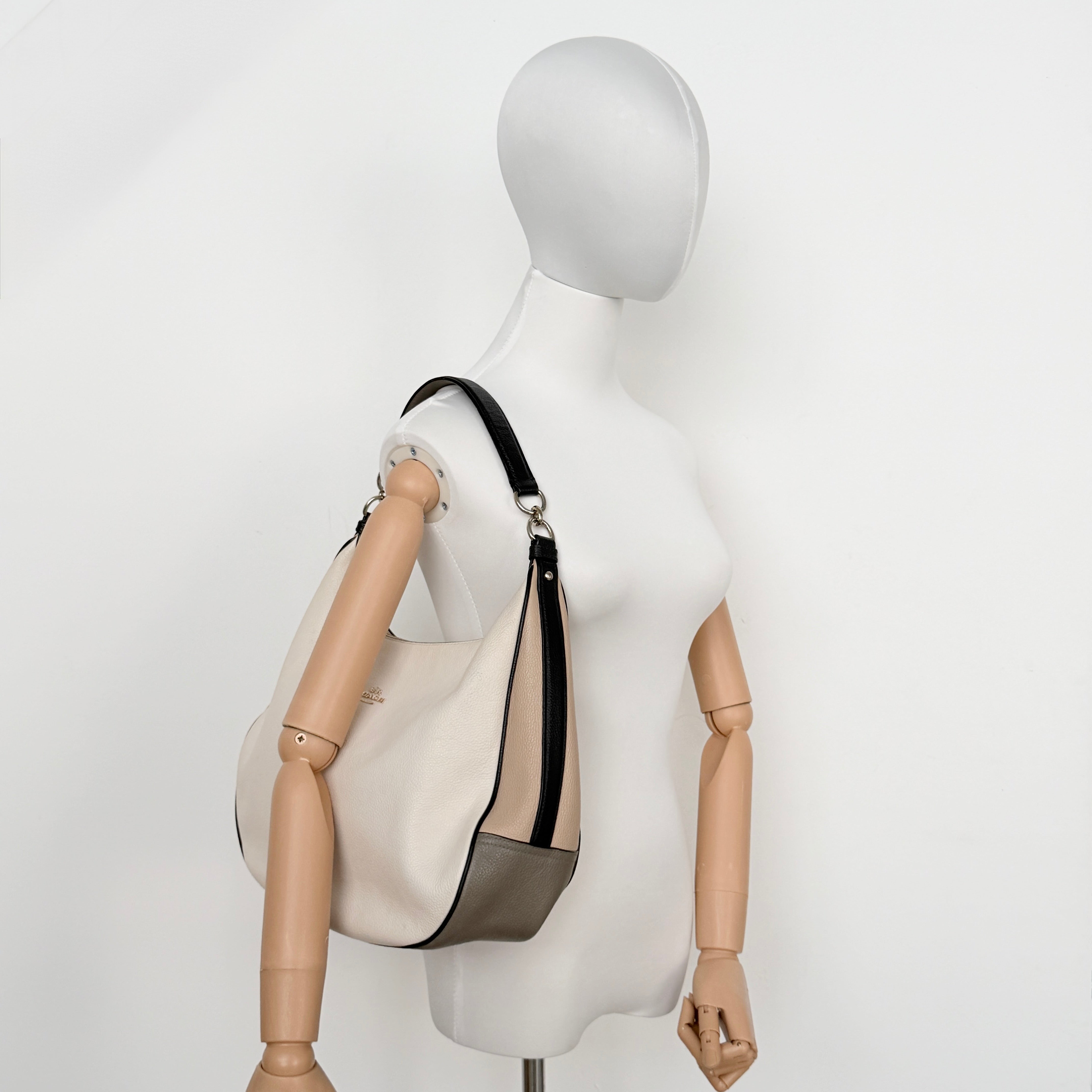 Coach Harley East West Hobo in cream and beige pebbled leather with a sculpted silhouette, black piping, and silver hardware.