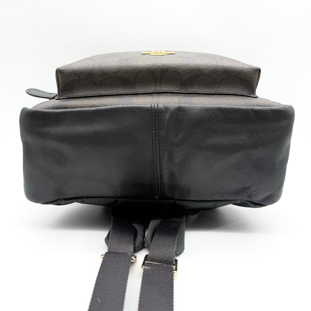 Coach Signature Charlie Backpack in brown and black canvas with gold-tone hardware and front zip pocket.