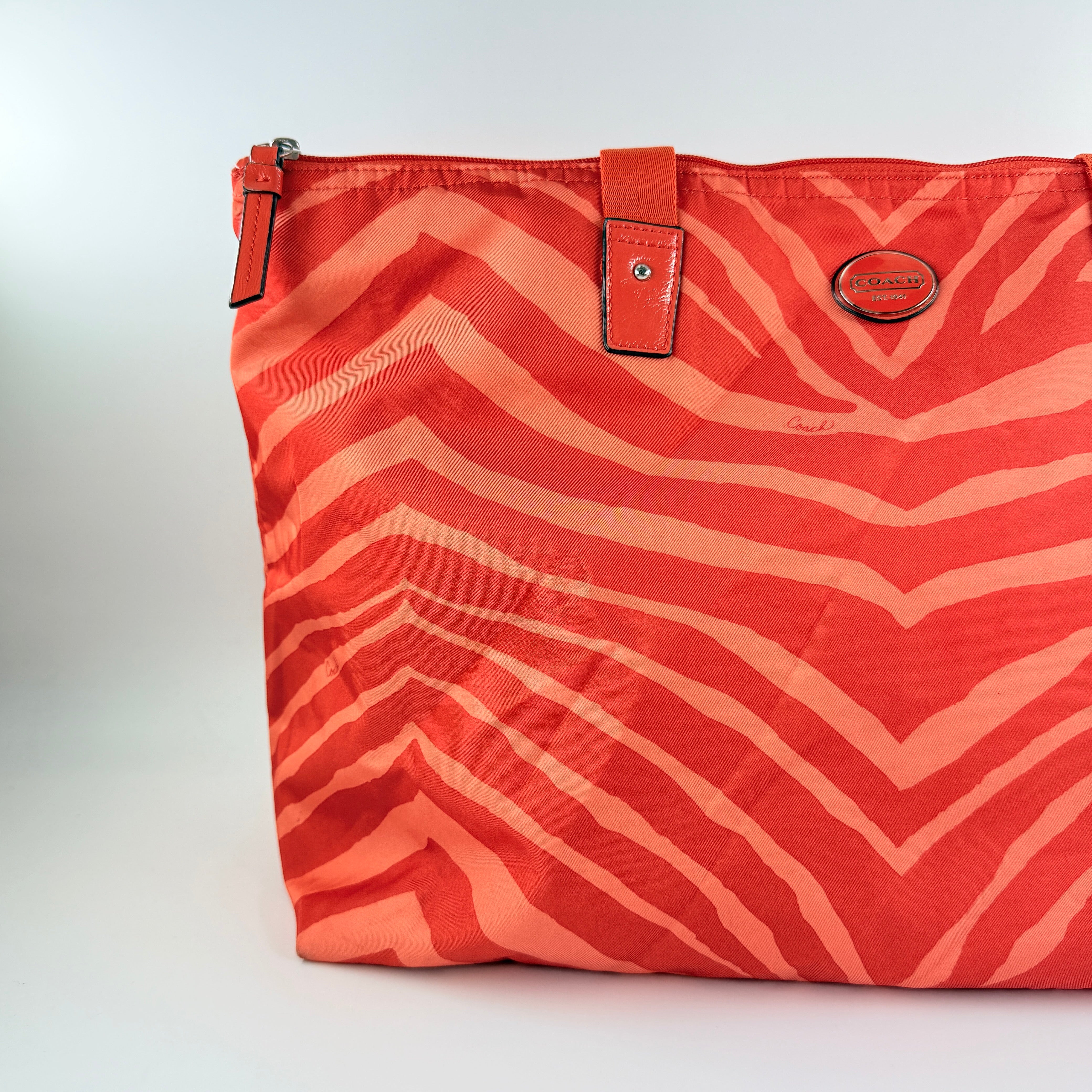 Coach Getaway Weekender tote and matching pouch in orange zebra print, with structured silhouette and bold colour.