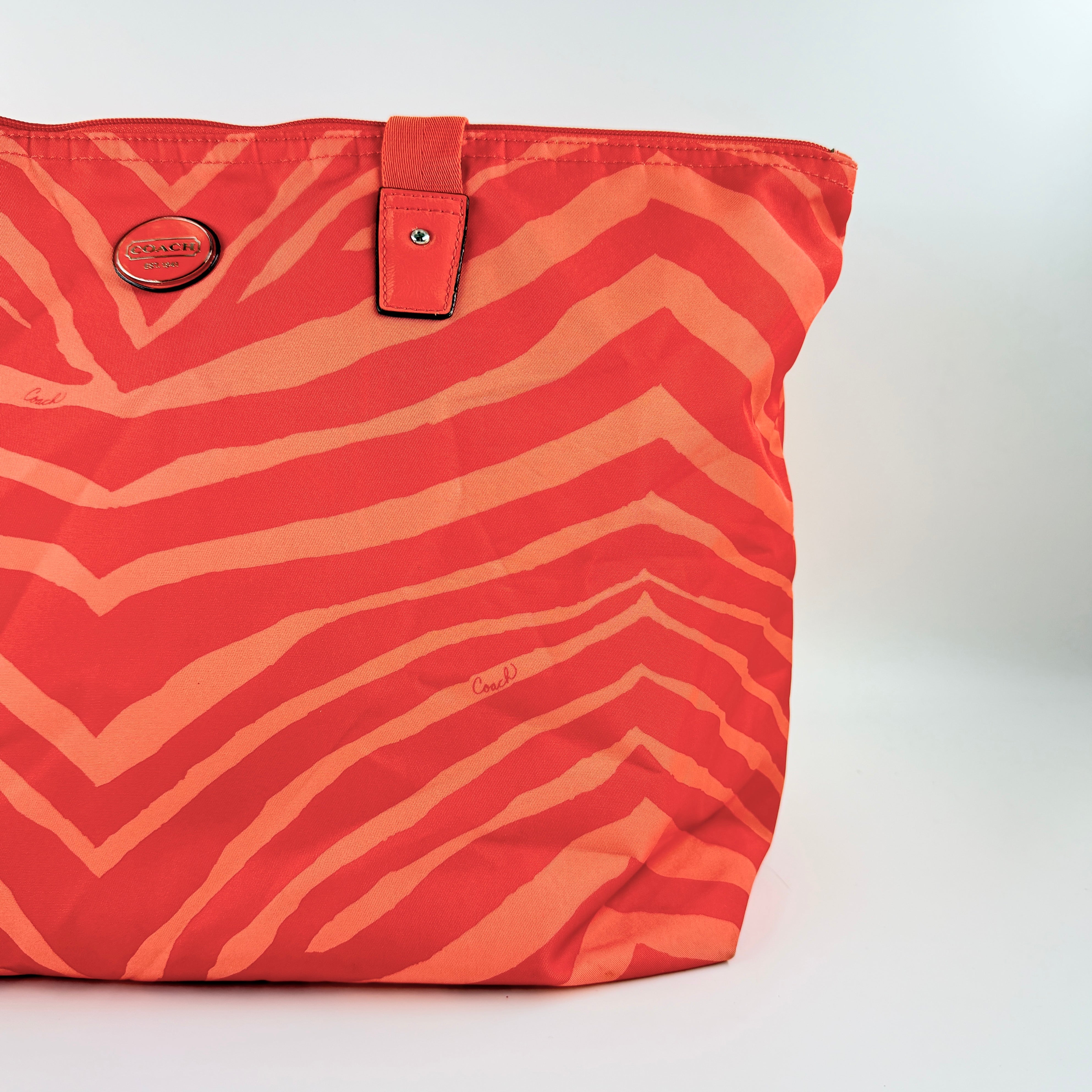 Coach Getaway Weekender tote and matching pouch in orange zebra print, with structured silhouette and bold colour.