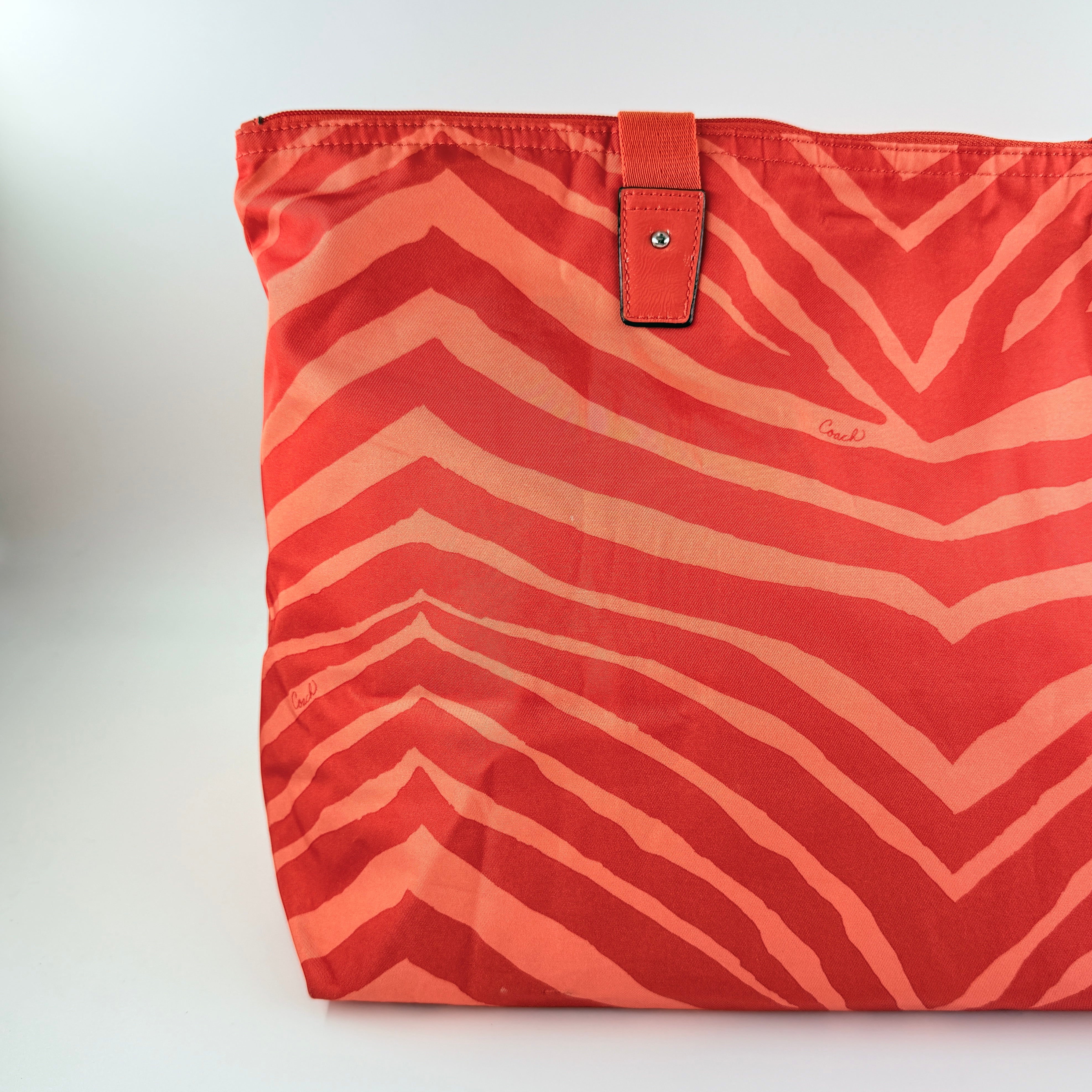 Coach Getaway Weekender tote and matching pouch in orange zebra print, with structured silhouette and bold colour.