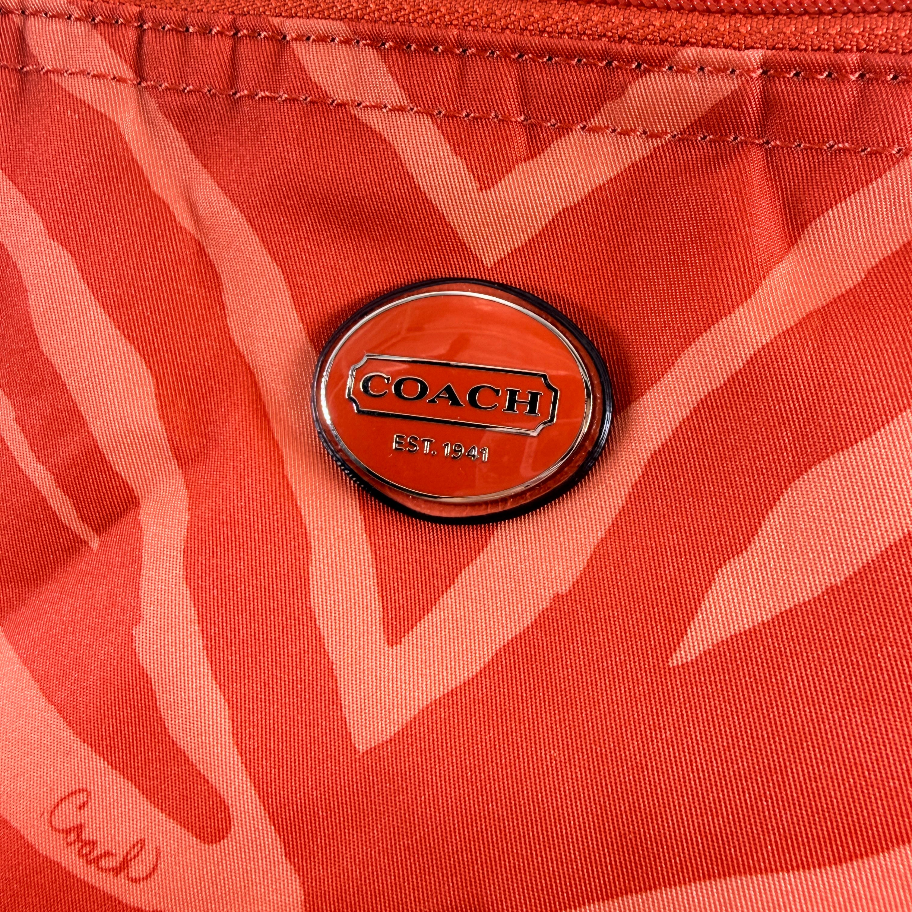 Coach Getaway Weekender tote and matching pouch in orange zebra print, with structured silhouette and bold colour.