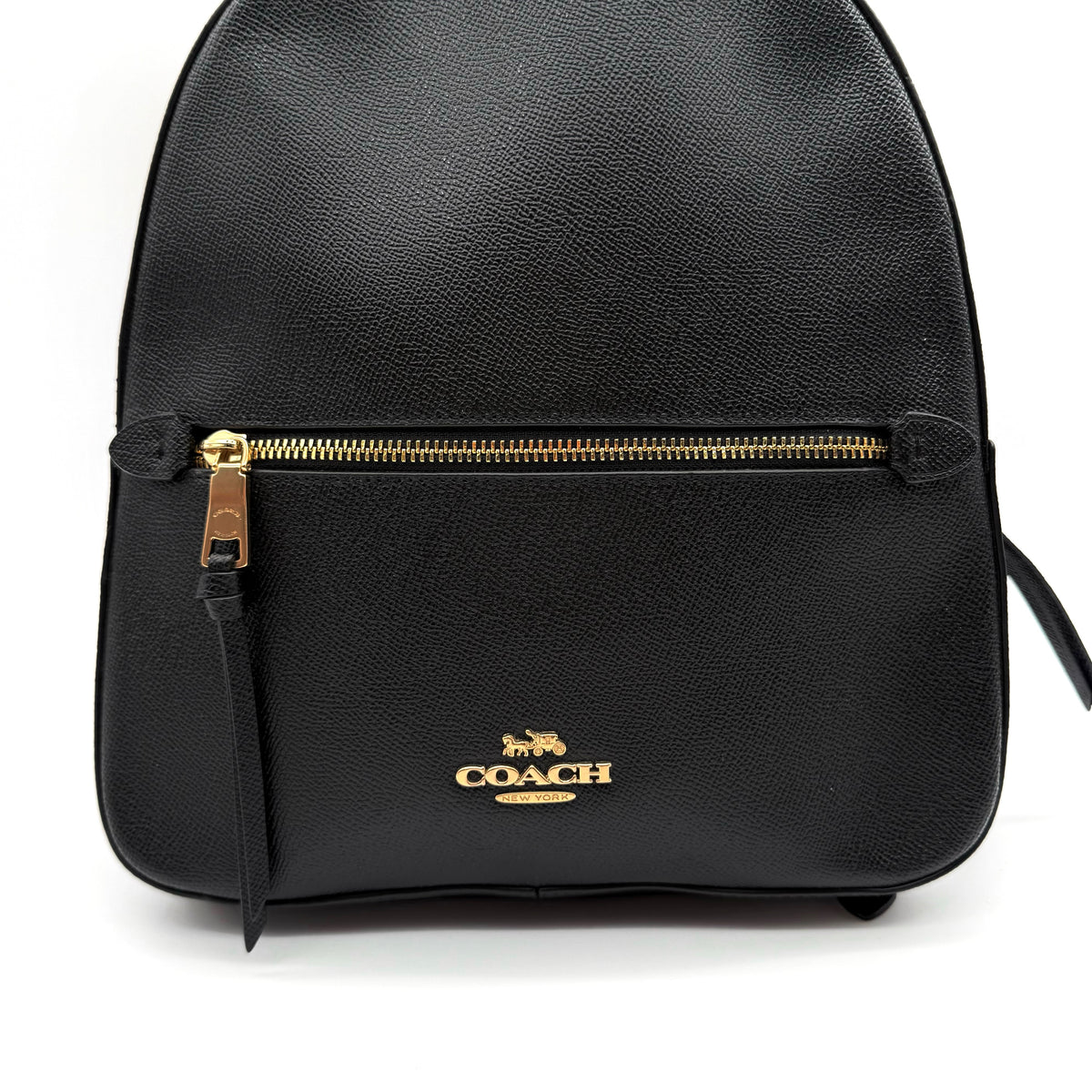 Coach Jordyn Leather Backpack in black grained leather with gold-tone hardware and minimal branding, photographed on white background.