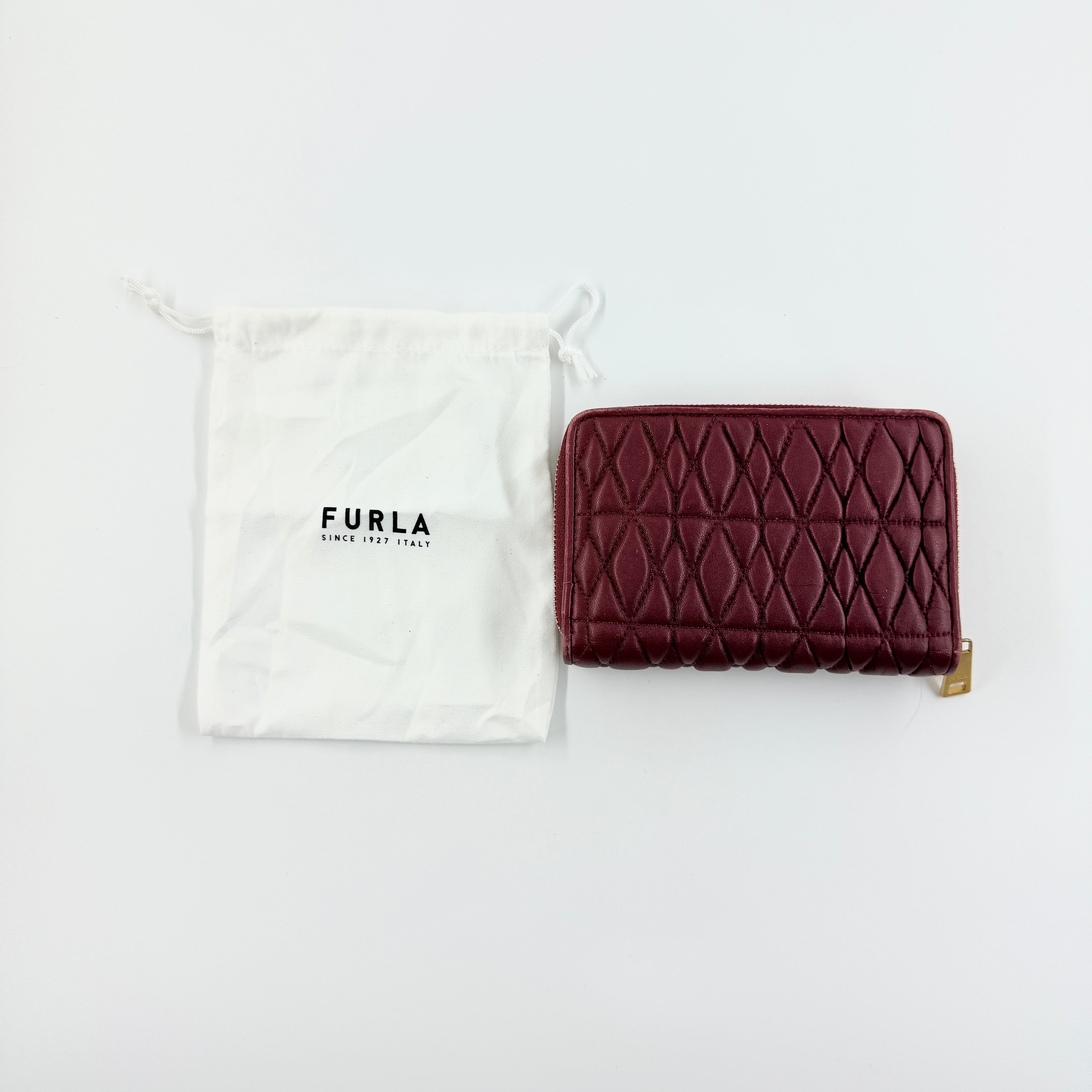 Furla quilted Cometa zip around wallet in deep burgundy leather with gold-tone hardware and diamond stitching.
