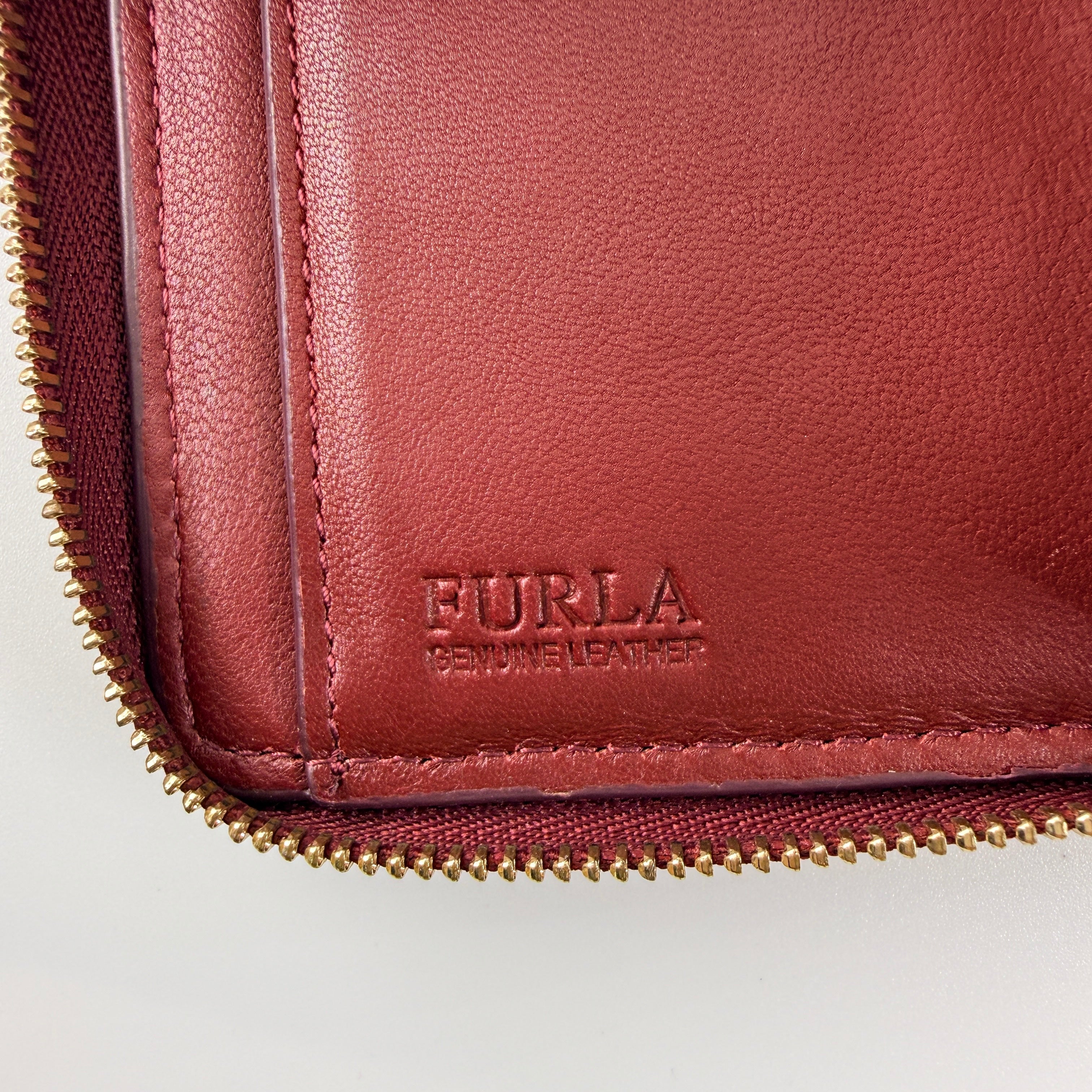 Furla quilted Cometa zip around wallet in deep burgundy leather with gold-tone hardware and diamond stitching.