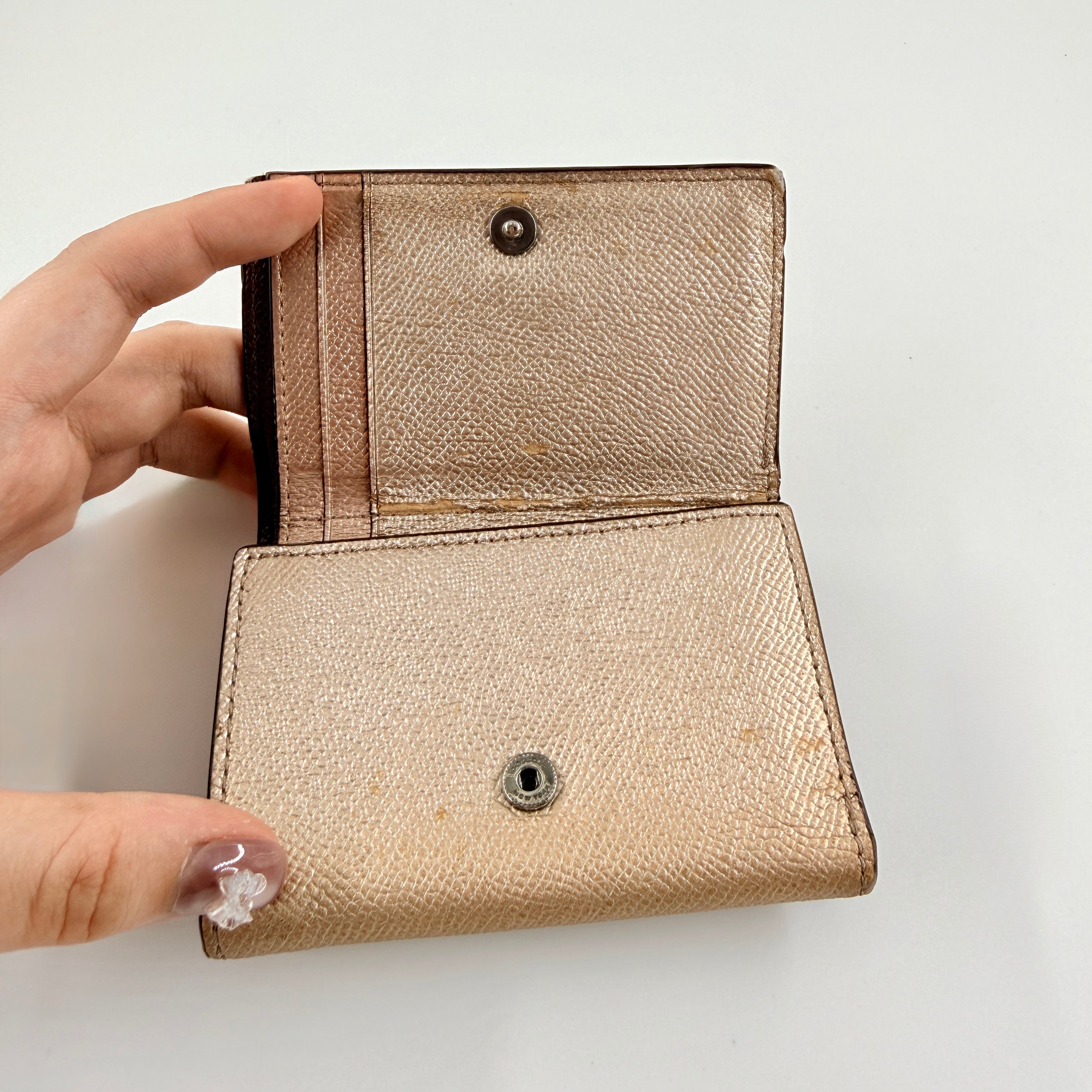 Coach metallic gold small flap wallet with silver logo plaque and crosshatch textured leather.
