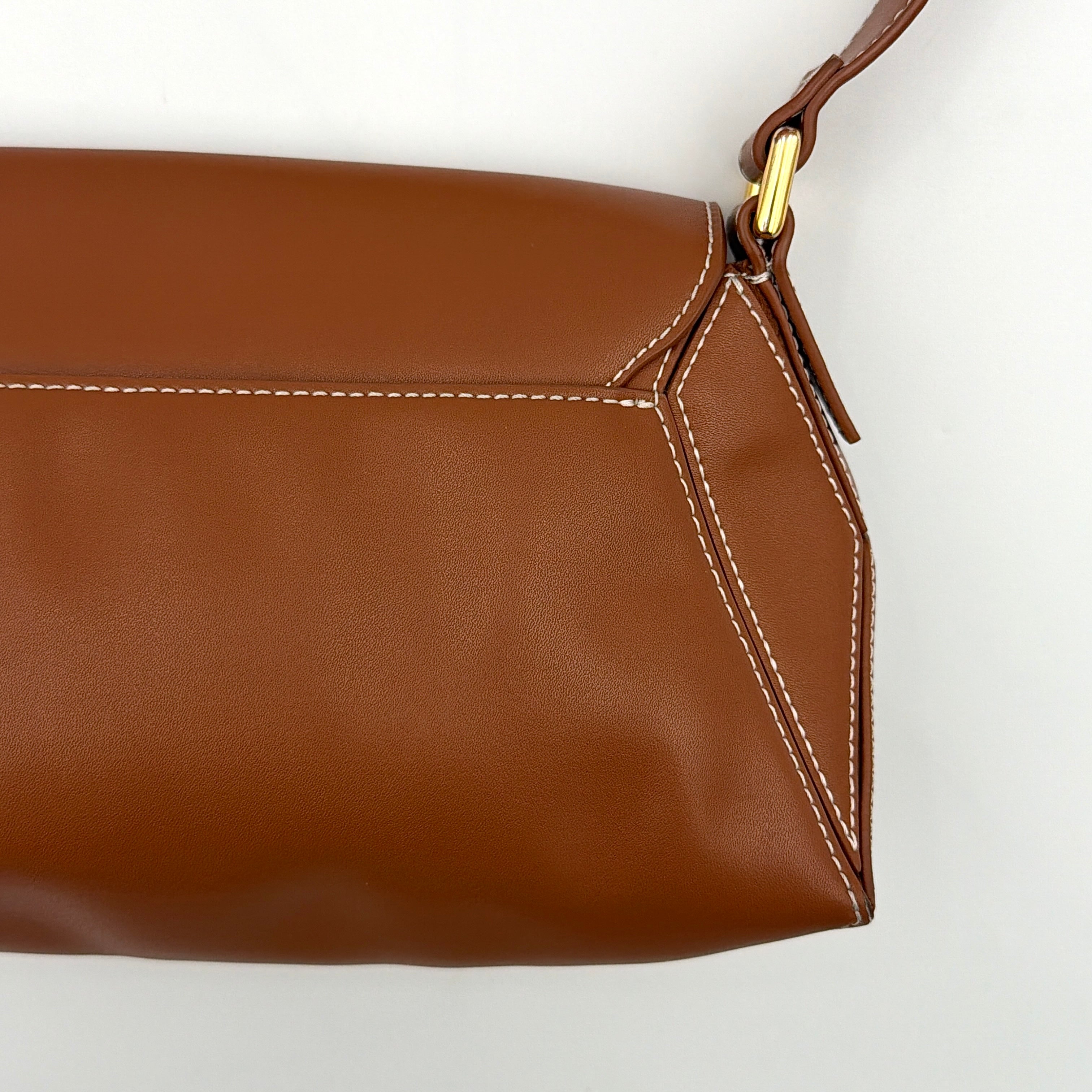 Charles & Keith Nasrin Geometric Crossbody Bag in brown faux leather with angular stitching, gold-tone hardware, and adjustable strap.