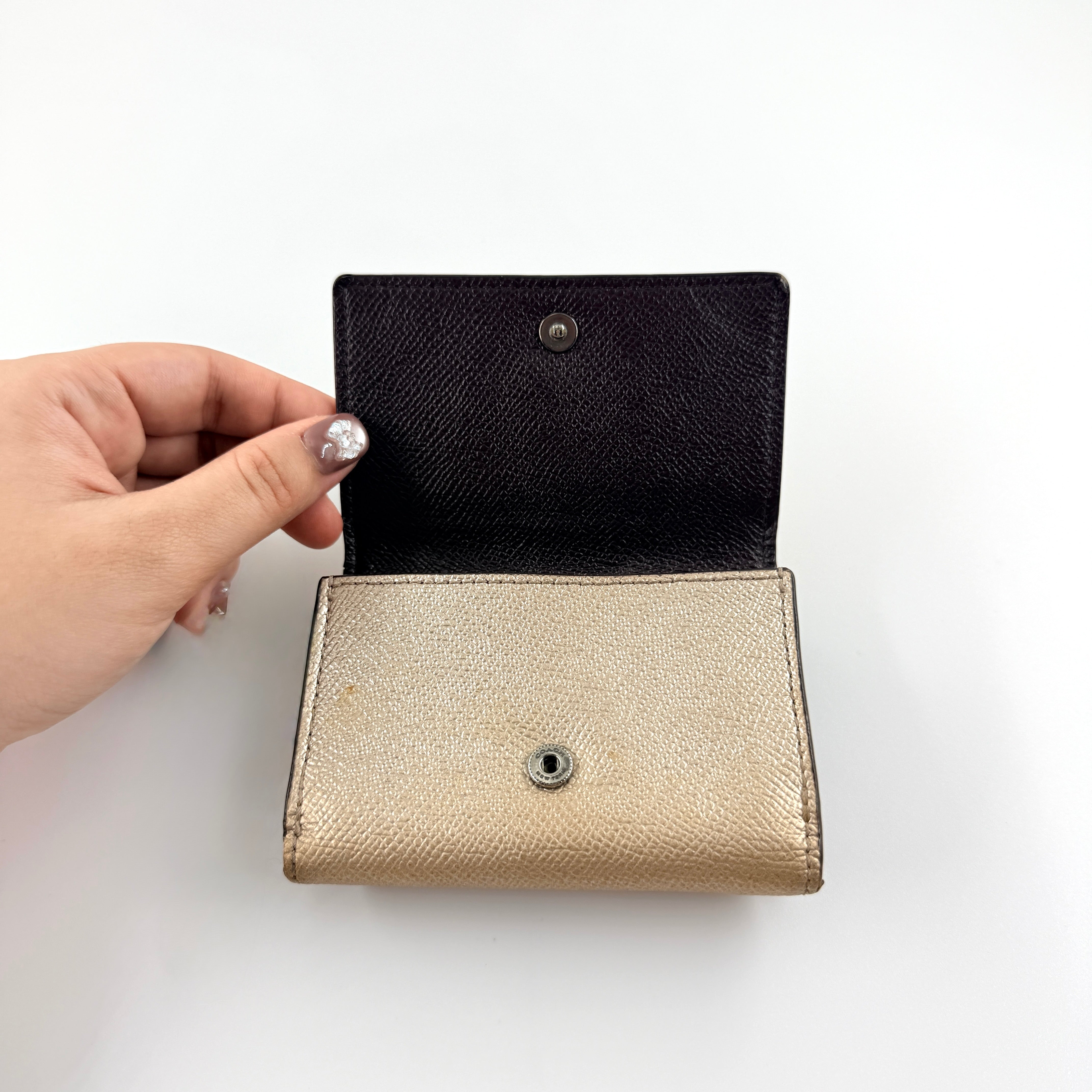 Coach metallic gold small flap wallet with silver logo plaque and crosshatch textured leather.