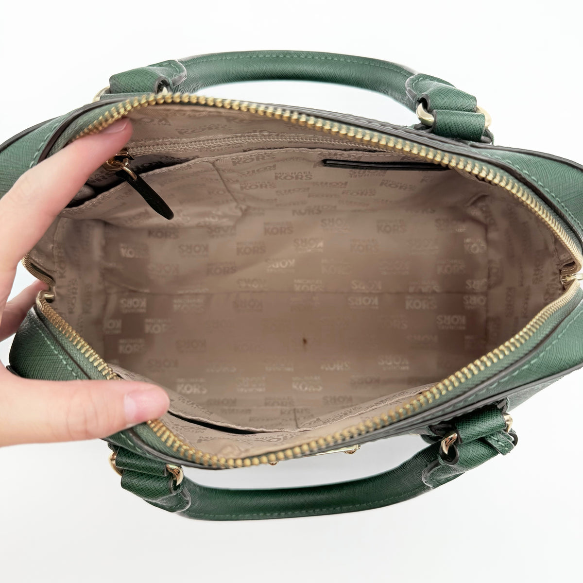 Michael Kors dark green Saffiano leather dome satchel with gold hardware and detachable strap, shown against a white background.