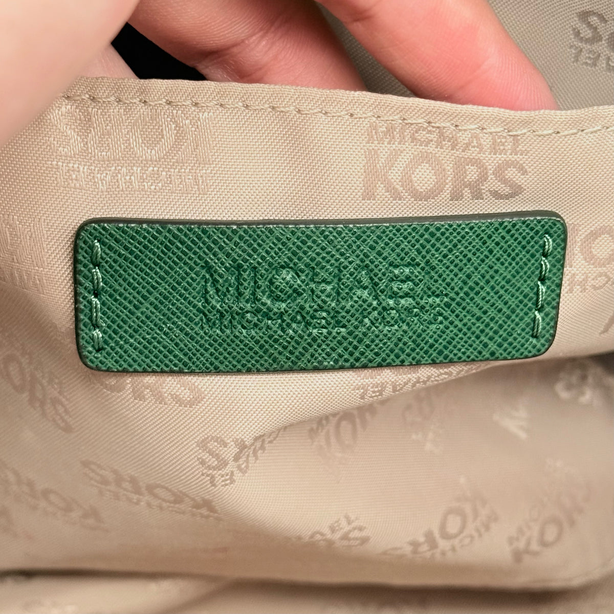 Michael Kors dark green Saffiano leather dome satchel with gold hardware and detachable strap, shown against a white background.