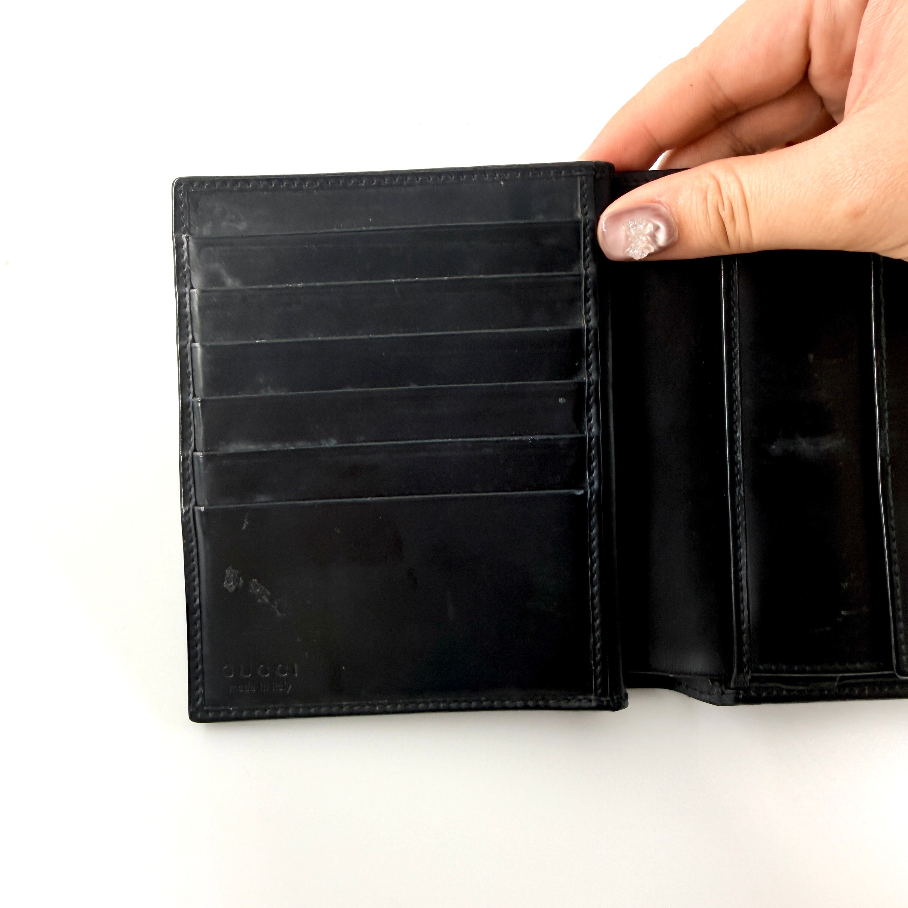 Gucci G Logo Bifold Wallet in black leather featuring a bold geometric G plaque and meticulously stitched edges.