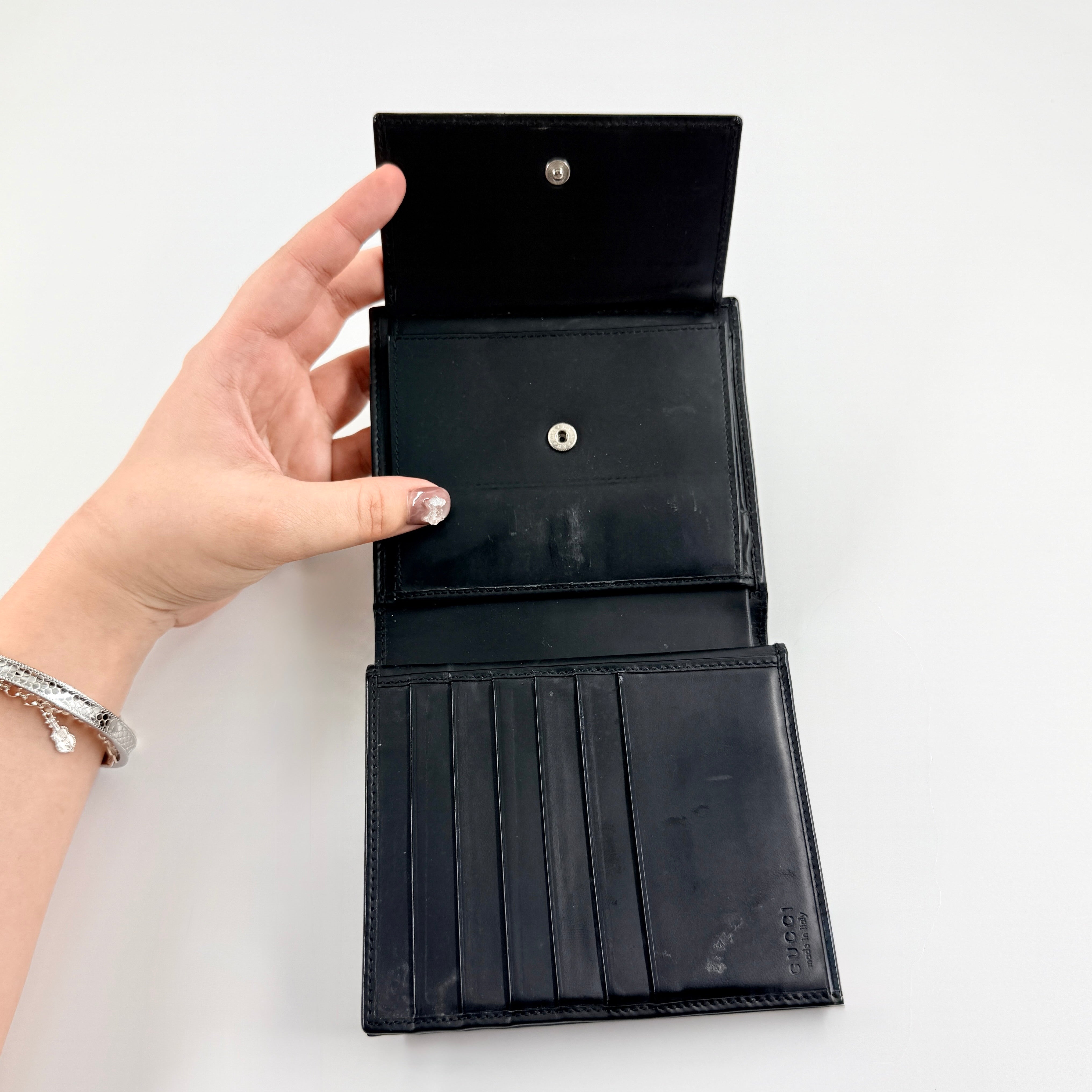 Gucci G Logo Bifold Wallet in black leather featuring a bold geometric G plaque and meticulously stitched edges.