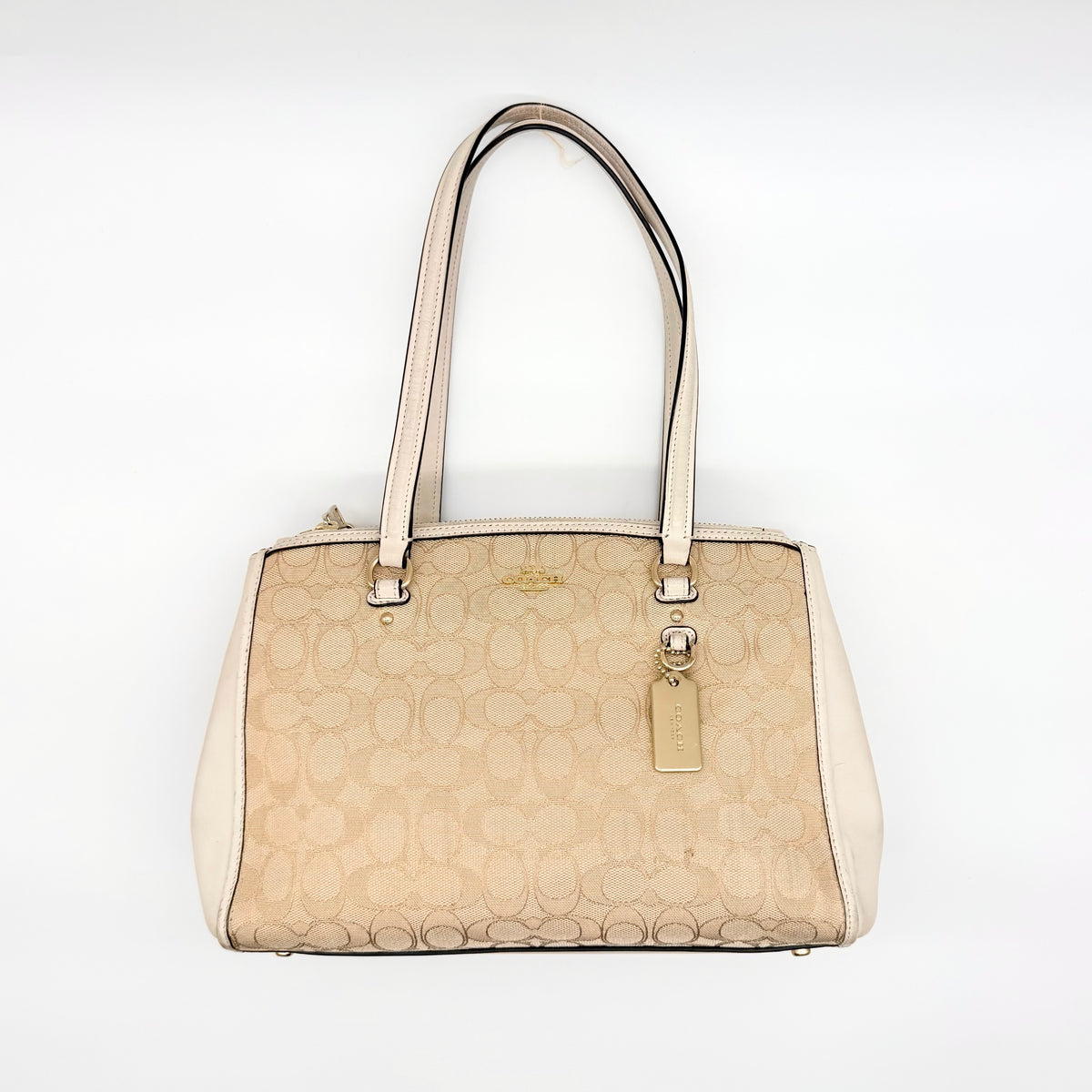 Coach Stanton Carryall in beige and ivory jacquard canvas with gold hardware and detachable strap, styled for everyday versatility.